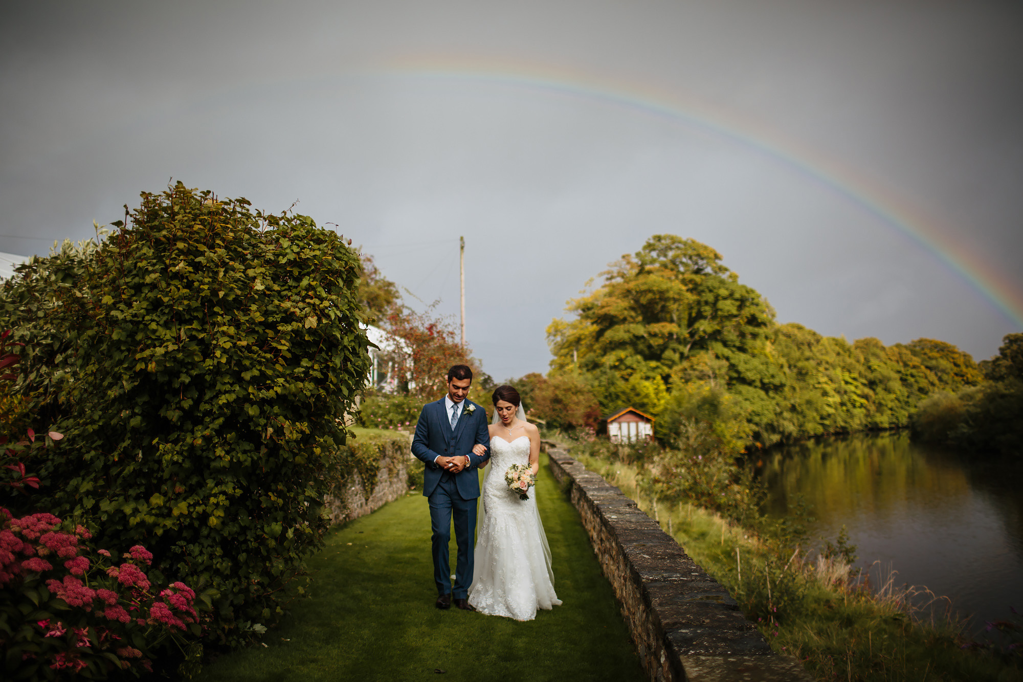 Bride and groom walking underneath a rainbow for a wedding portrait in Yorkshire