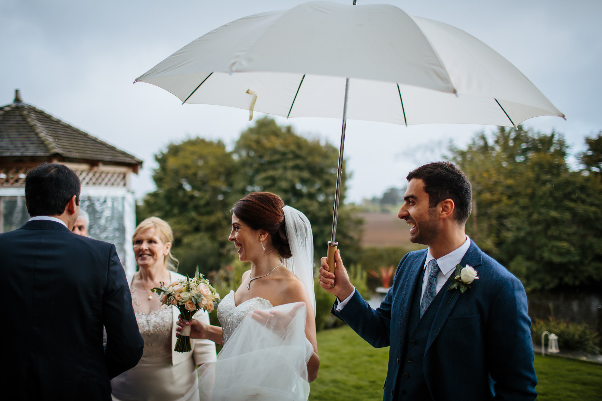 Groom holds an umbrella during a wet wedding in Yorkshire