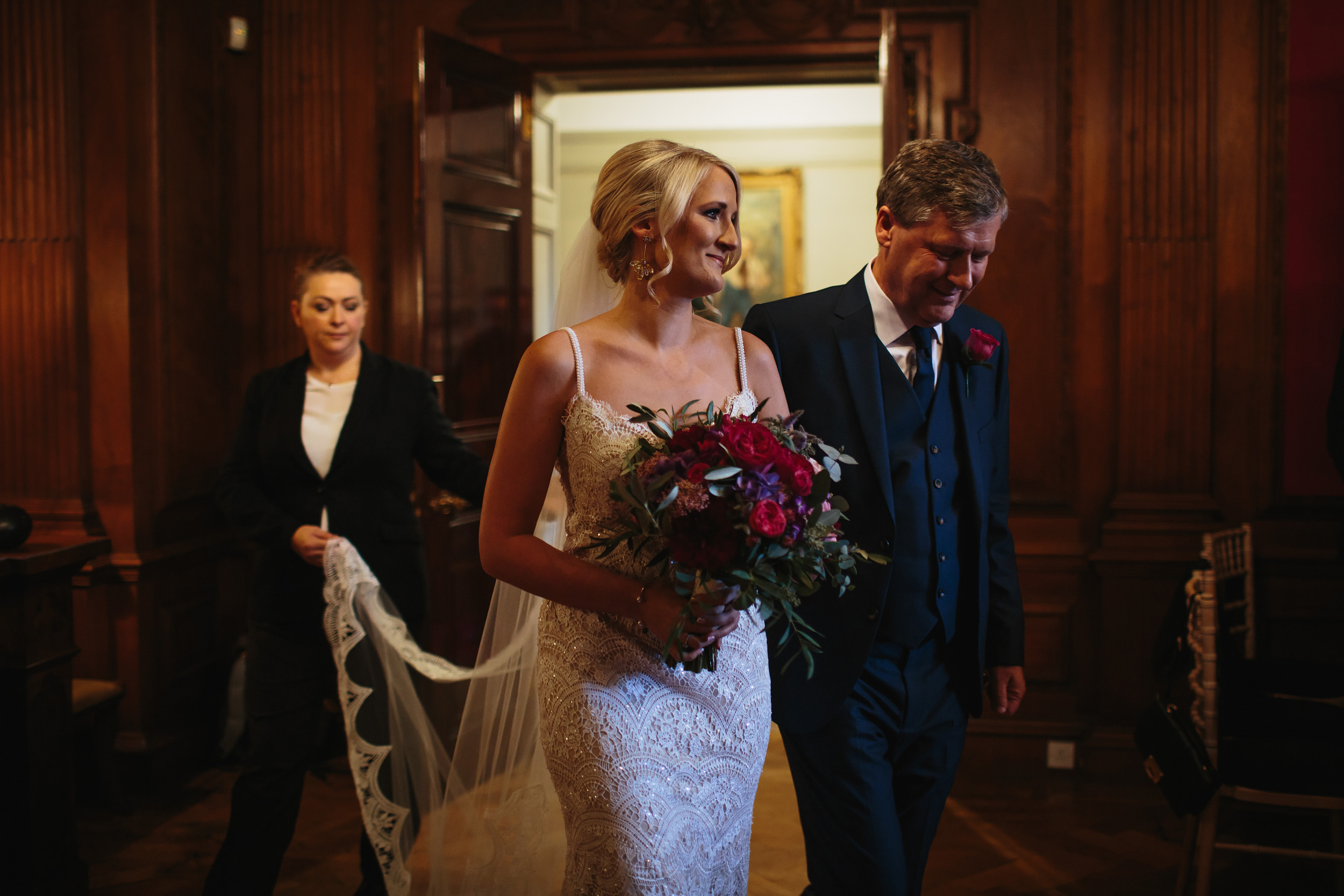 Bride enters her wedding holding her bouquet with her father