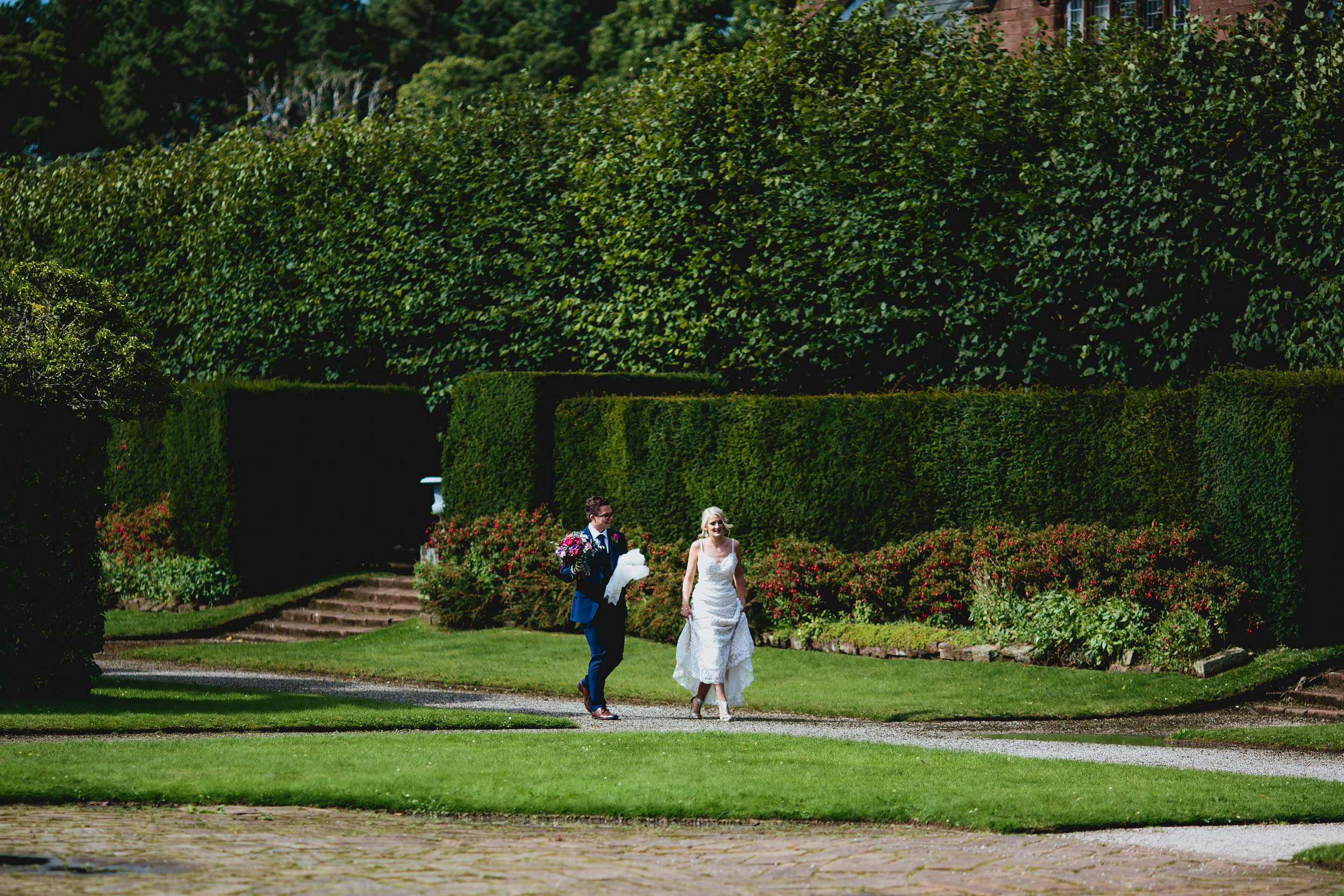 Bride and groom stroll through the gardens at their wedding venue