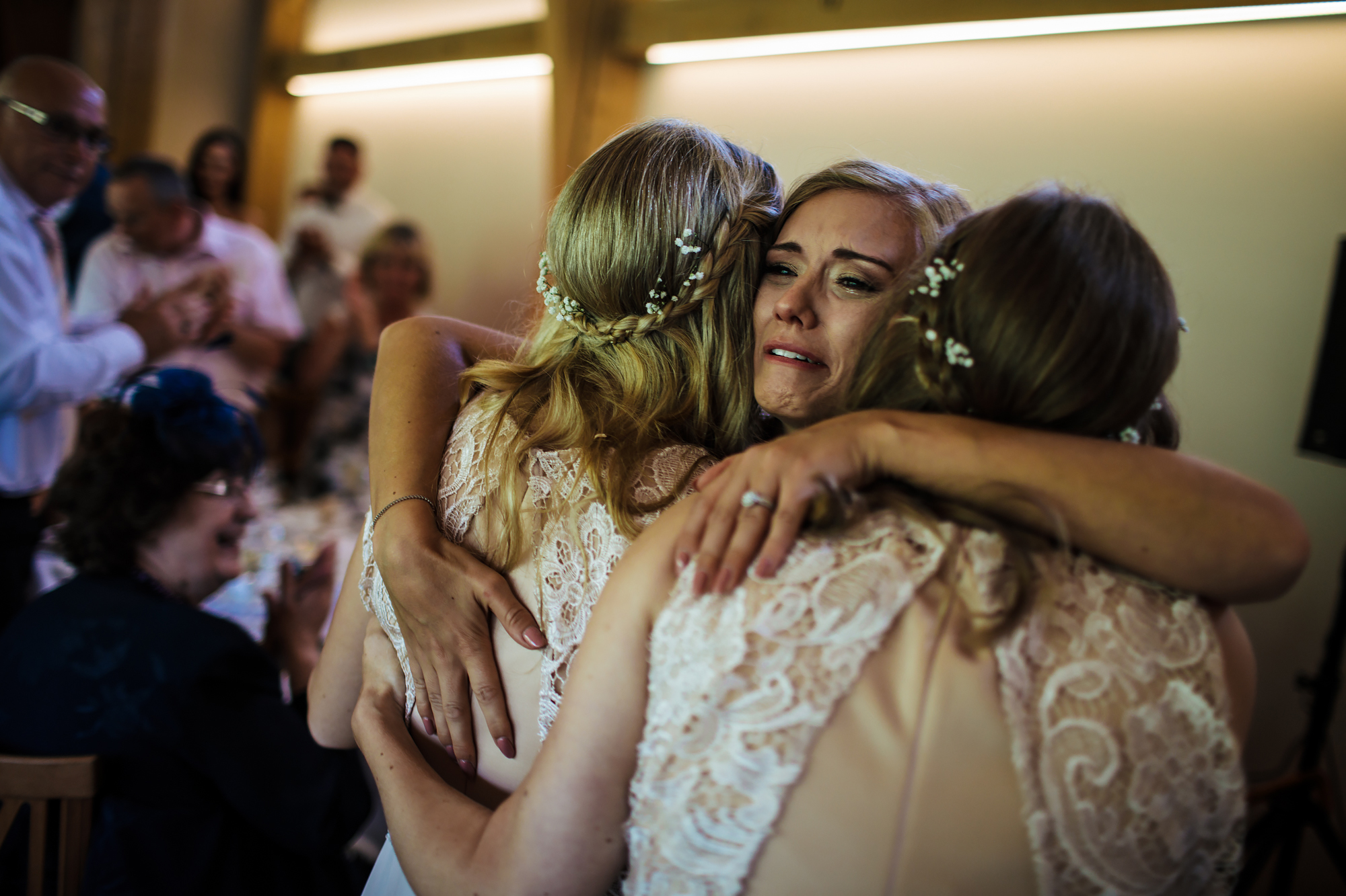 Bride hugging sisters at her emotional wedding