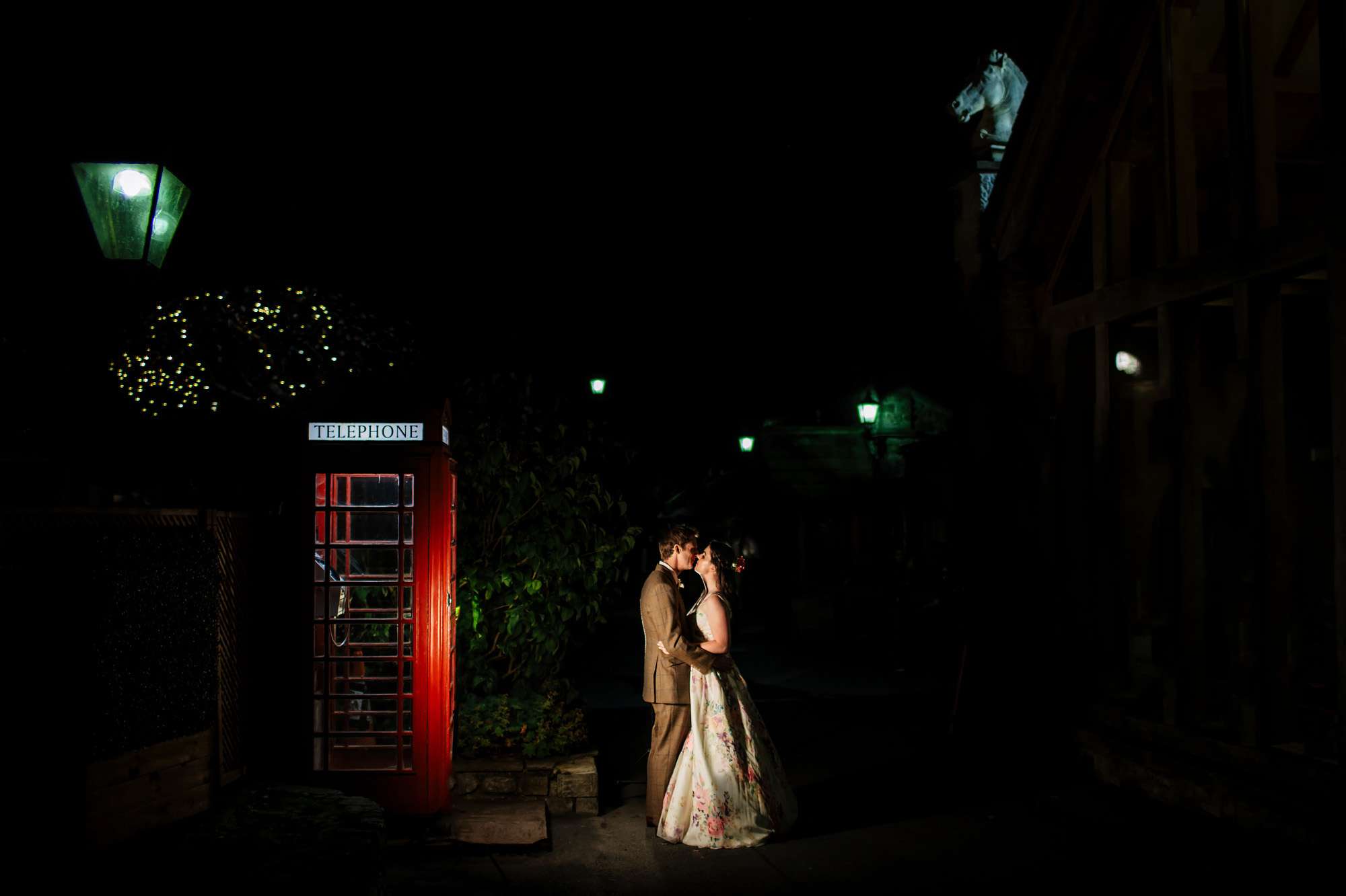 Bride and groom kissing by a red phone box at a Yorkshire Wedding