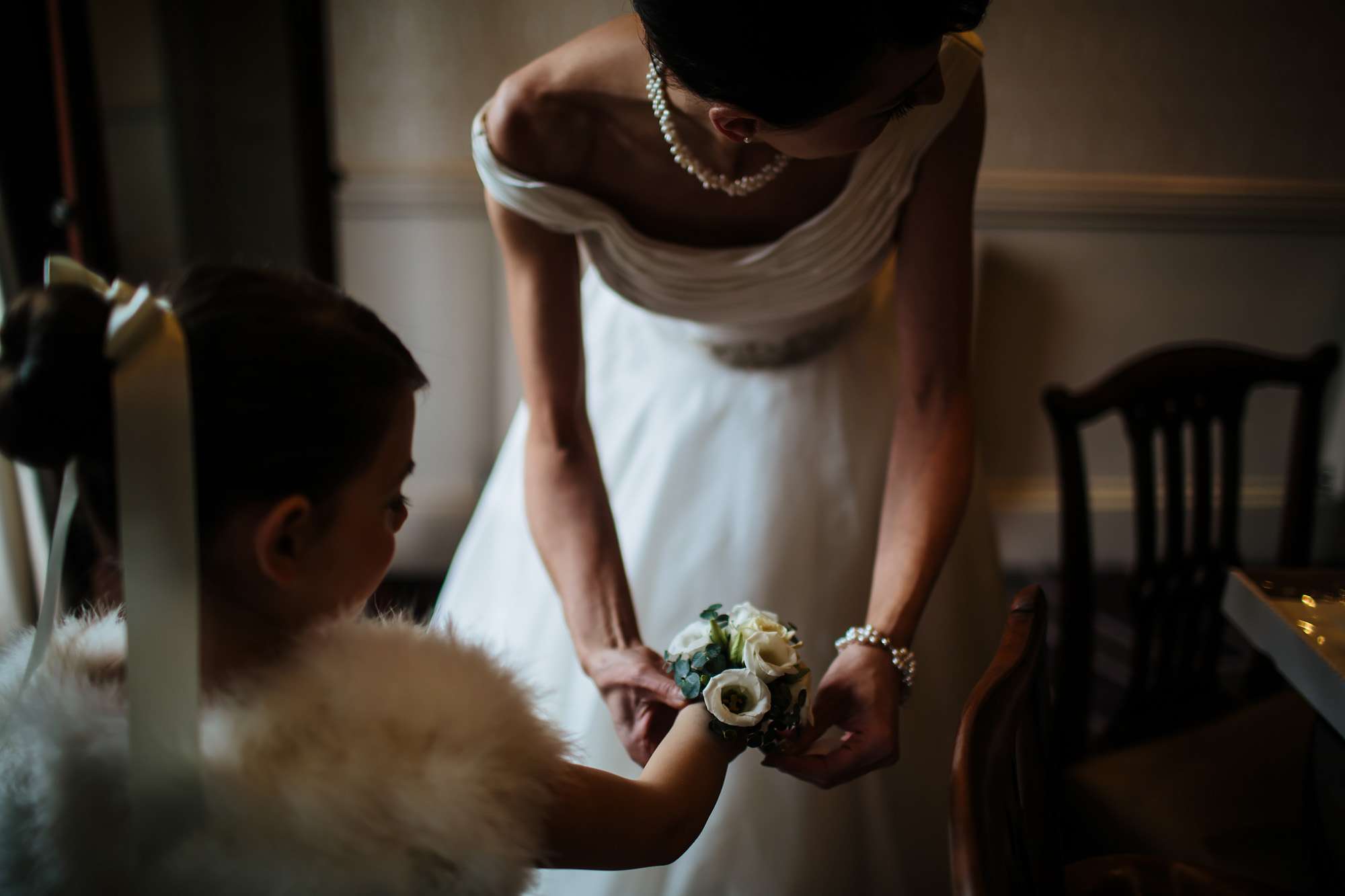 Bride attaches a flower bracelet to her daughter bridesmaid