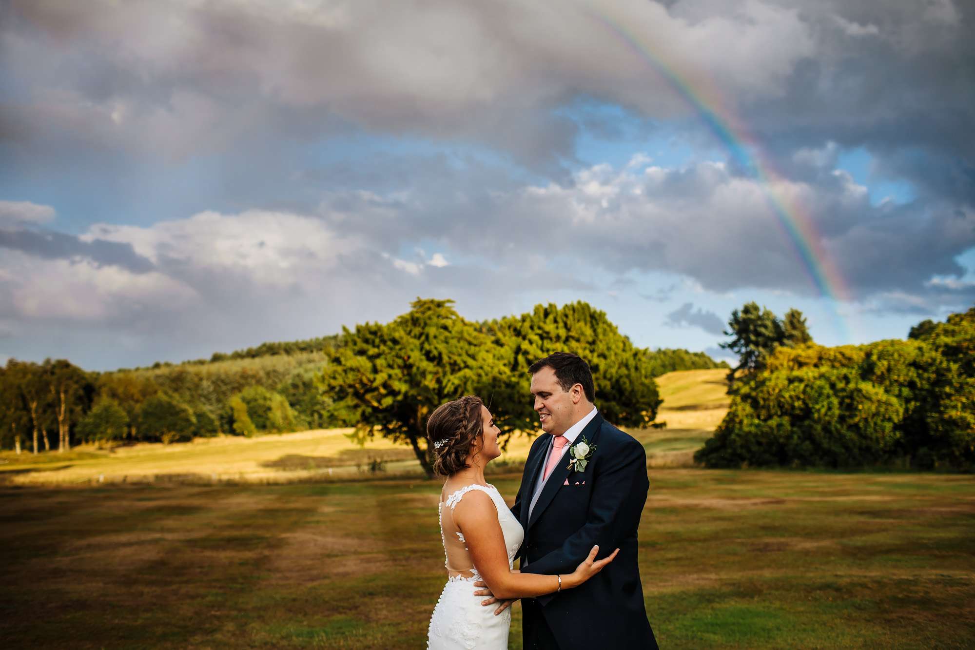 Bride and groom portrait with a rainbow in the background