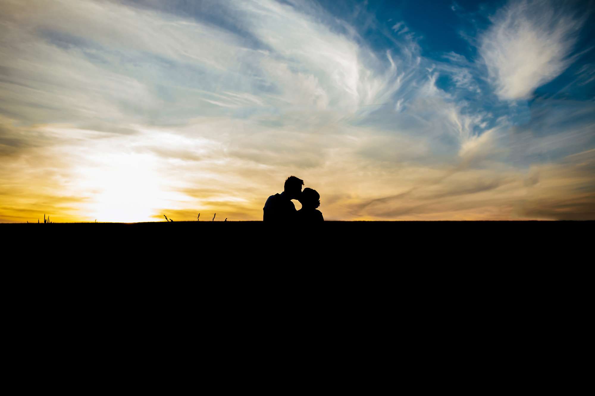 Sunset silhouette of a bride and groom kissing