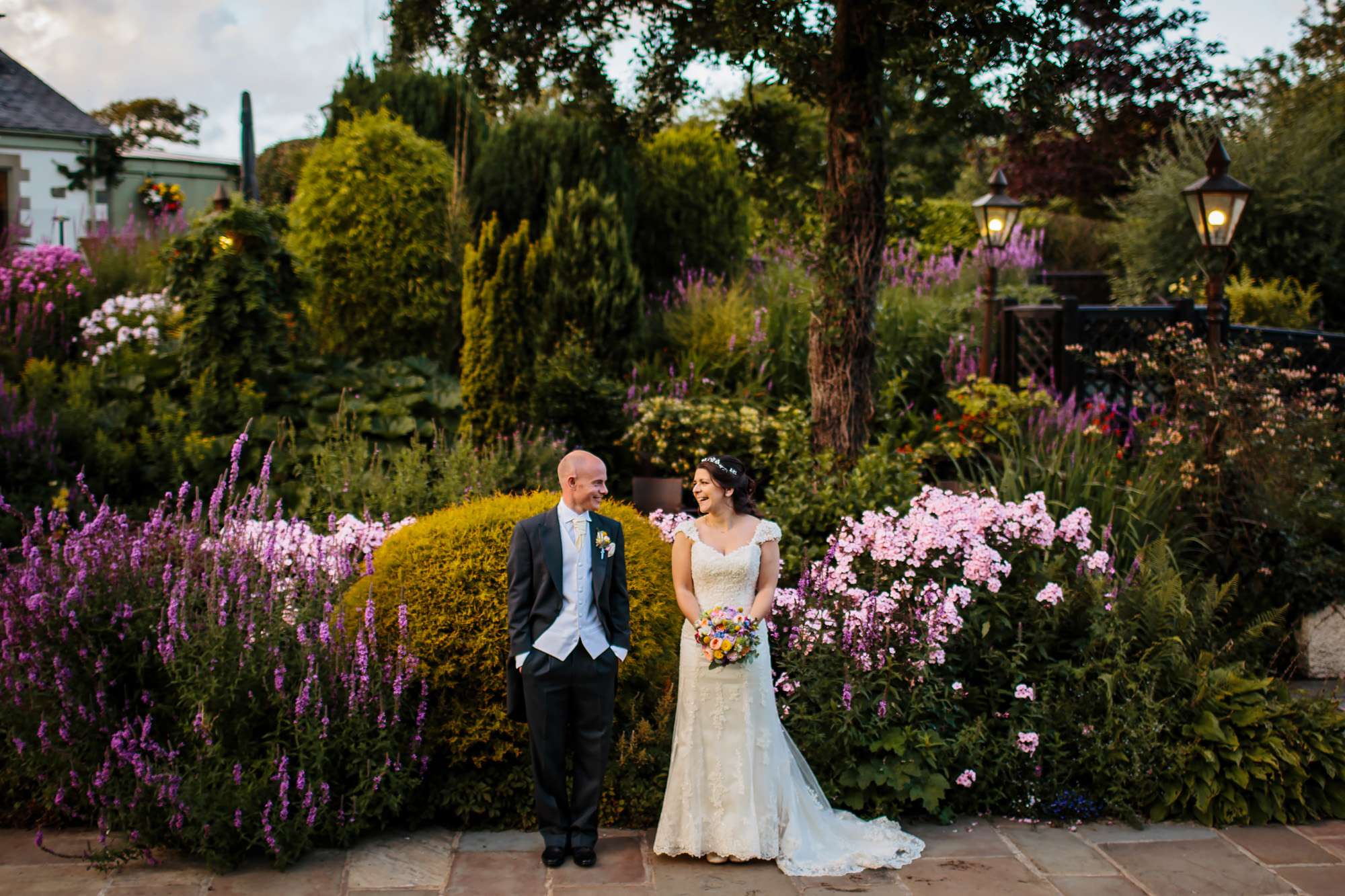 Bride and groom laughing in front of a flower bed in Yorkshire