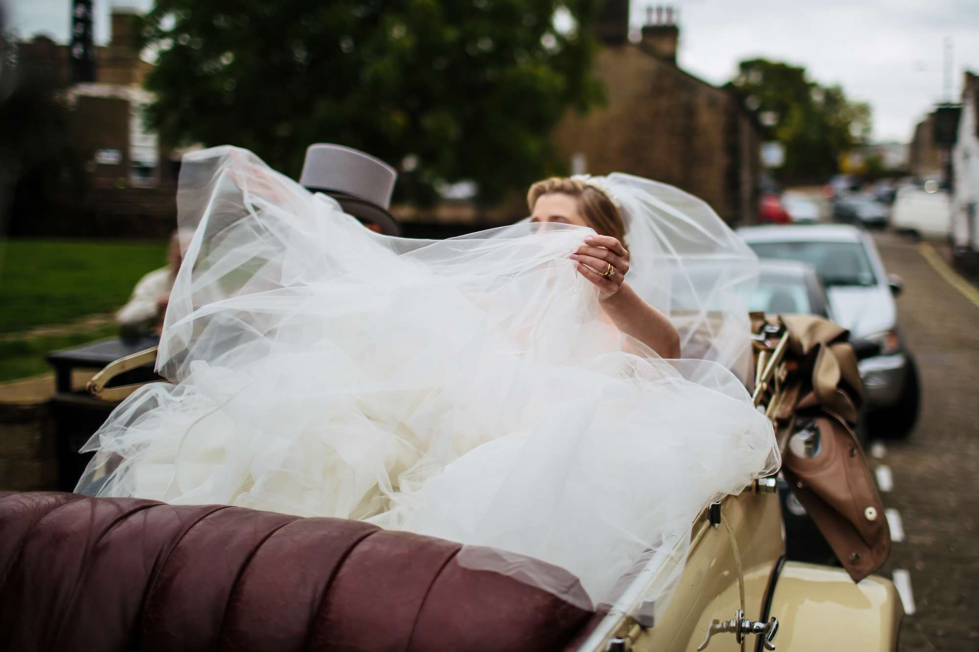 Bride adjusts her huge dress in her wedding car