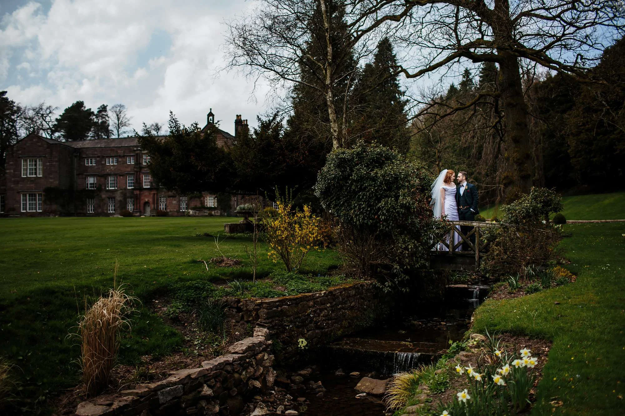 Bride and groom standing on a bridge in the gardens of Browsholme Hall Wedding