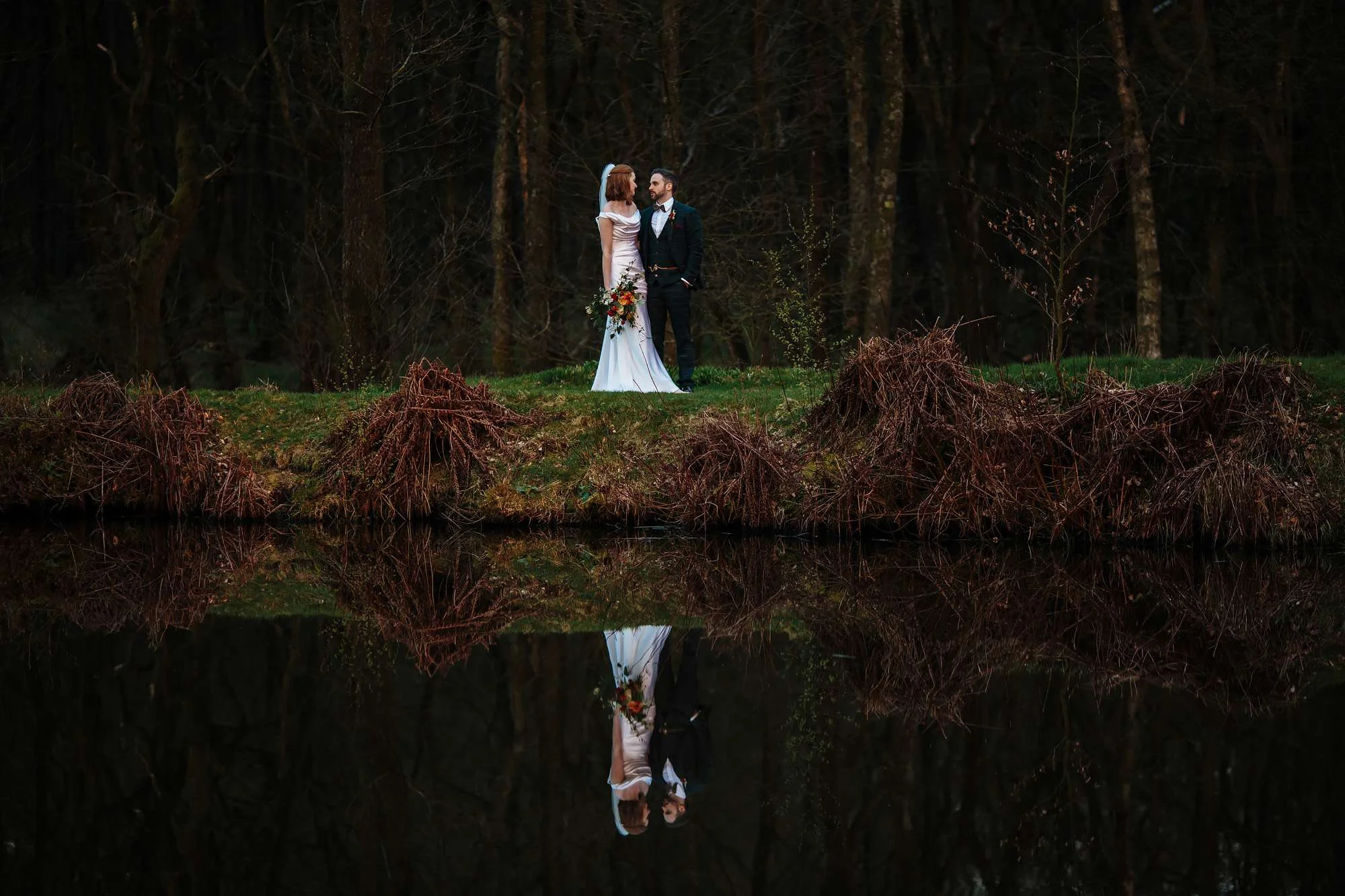 Bride and groom pose by the lake at their wedding