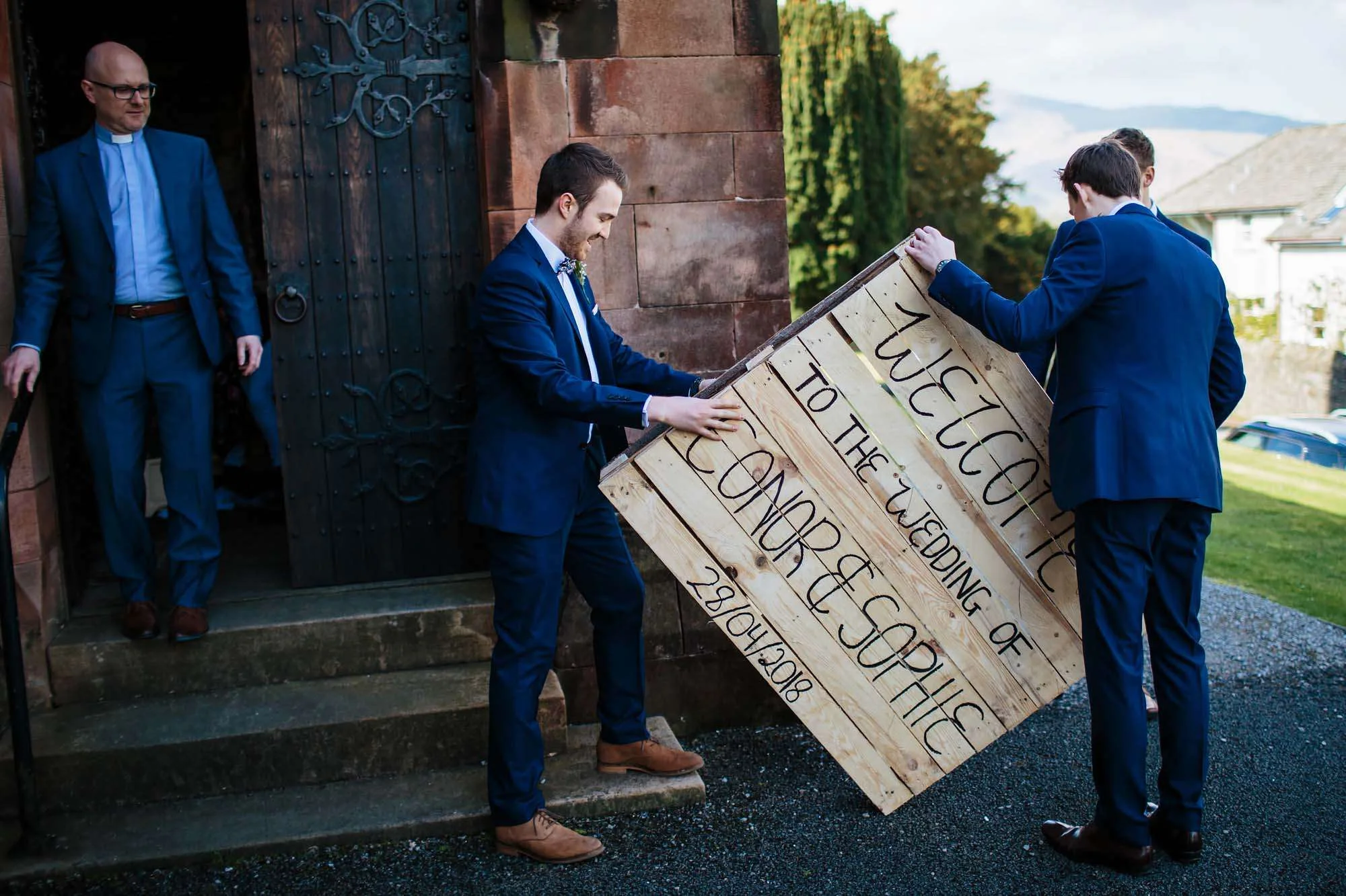 Erecting the wedding sign as vicar looks on