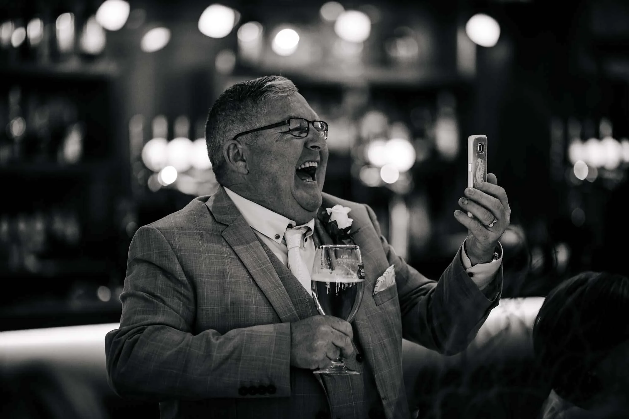Wedding guest laughing at his mobile phone