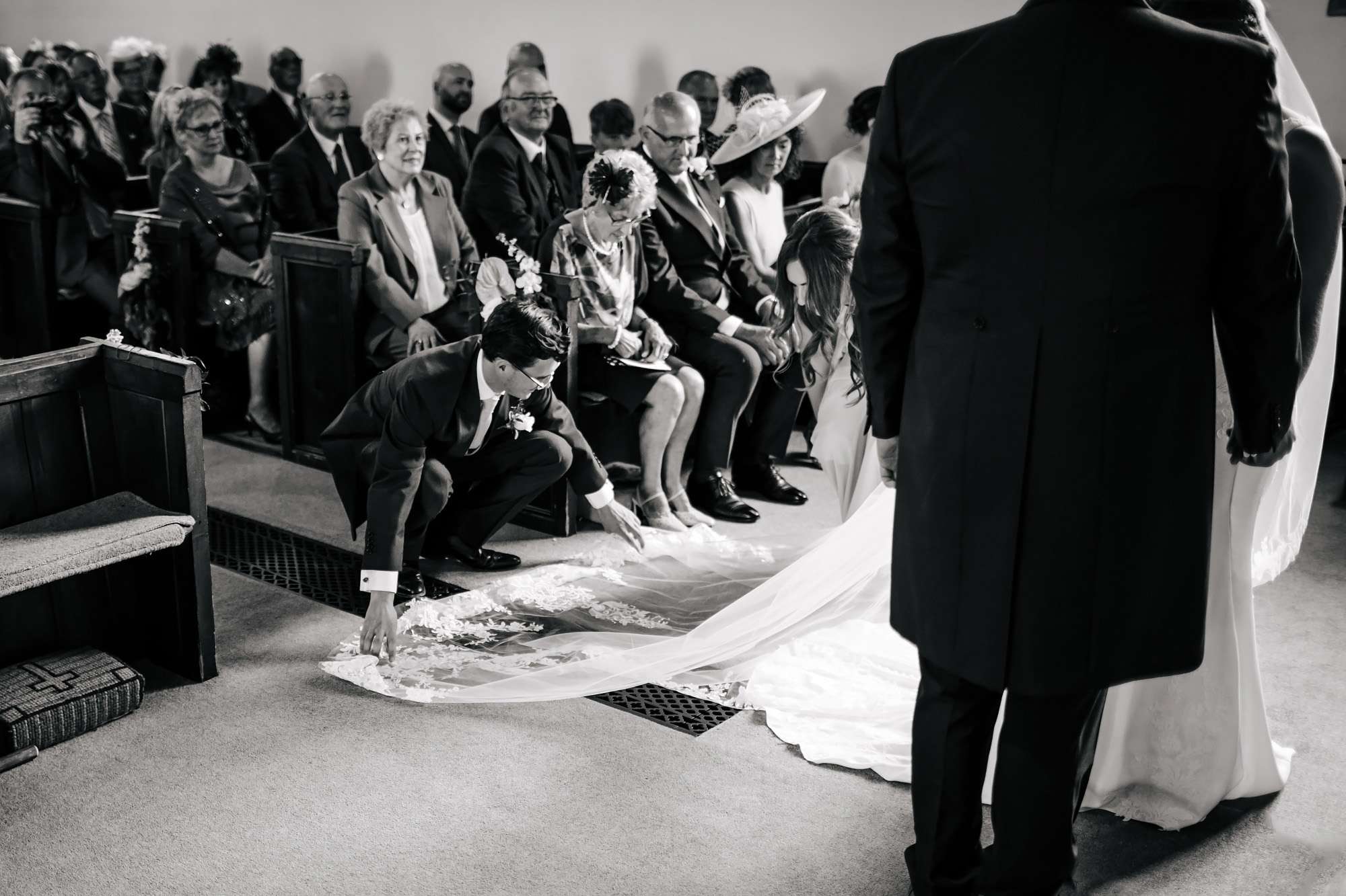 Best man adjusting the bride's dress in the church