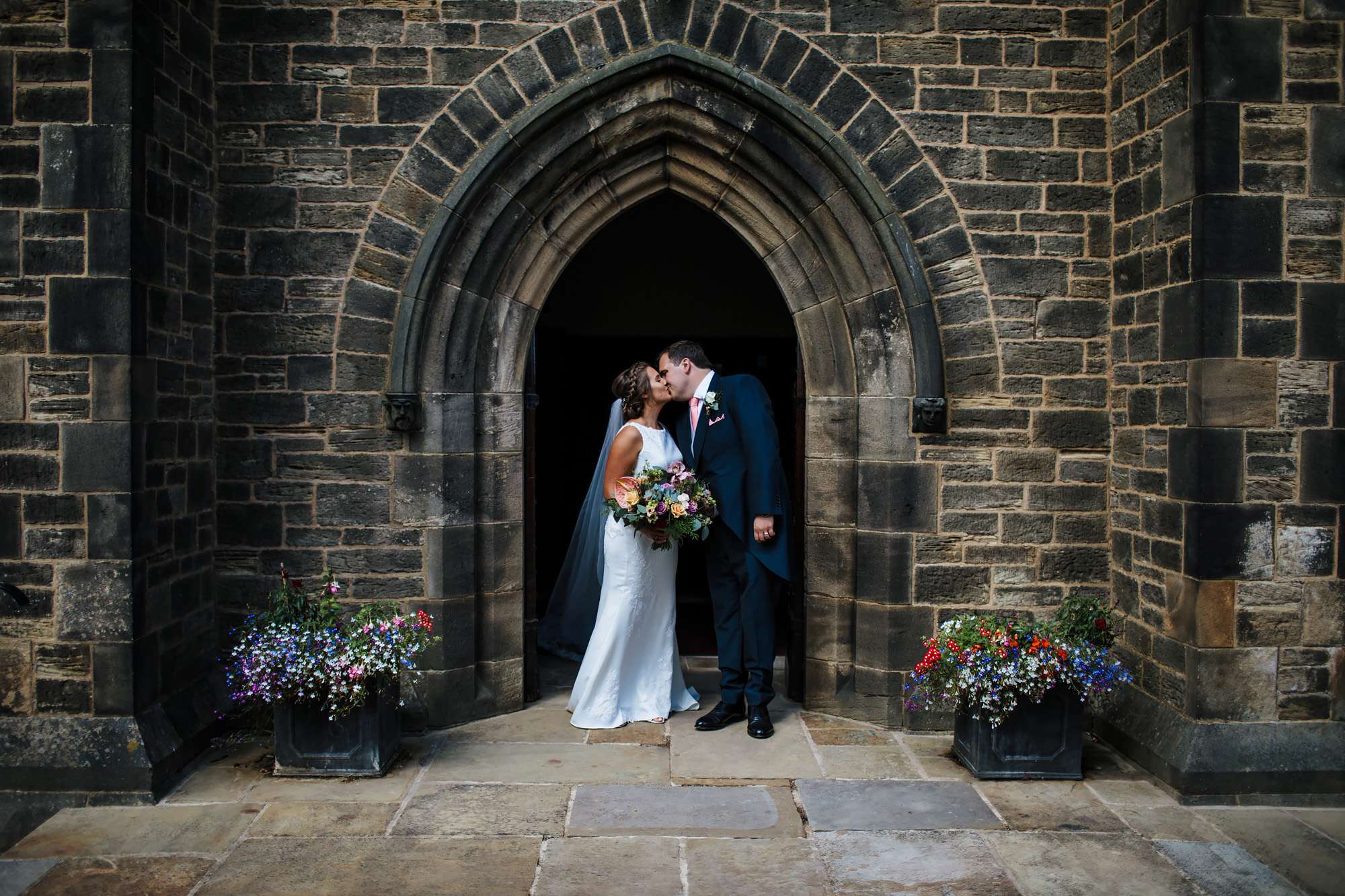 Bride and groom kissing outside a church in Huddersfield