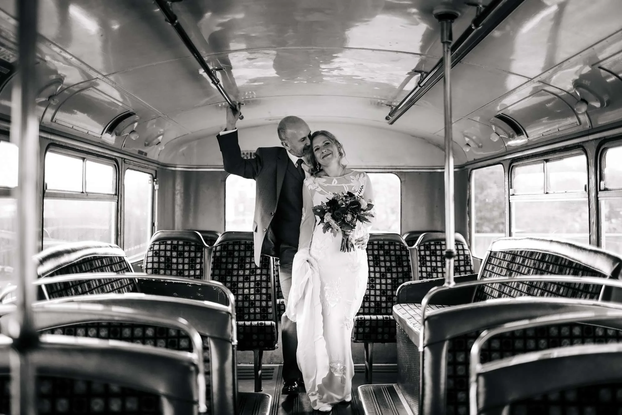 Bride and groom posing on the bus at their wedding