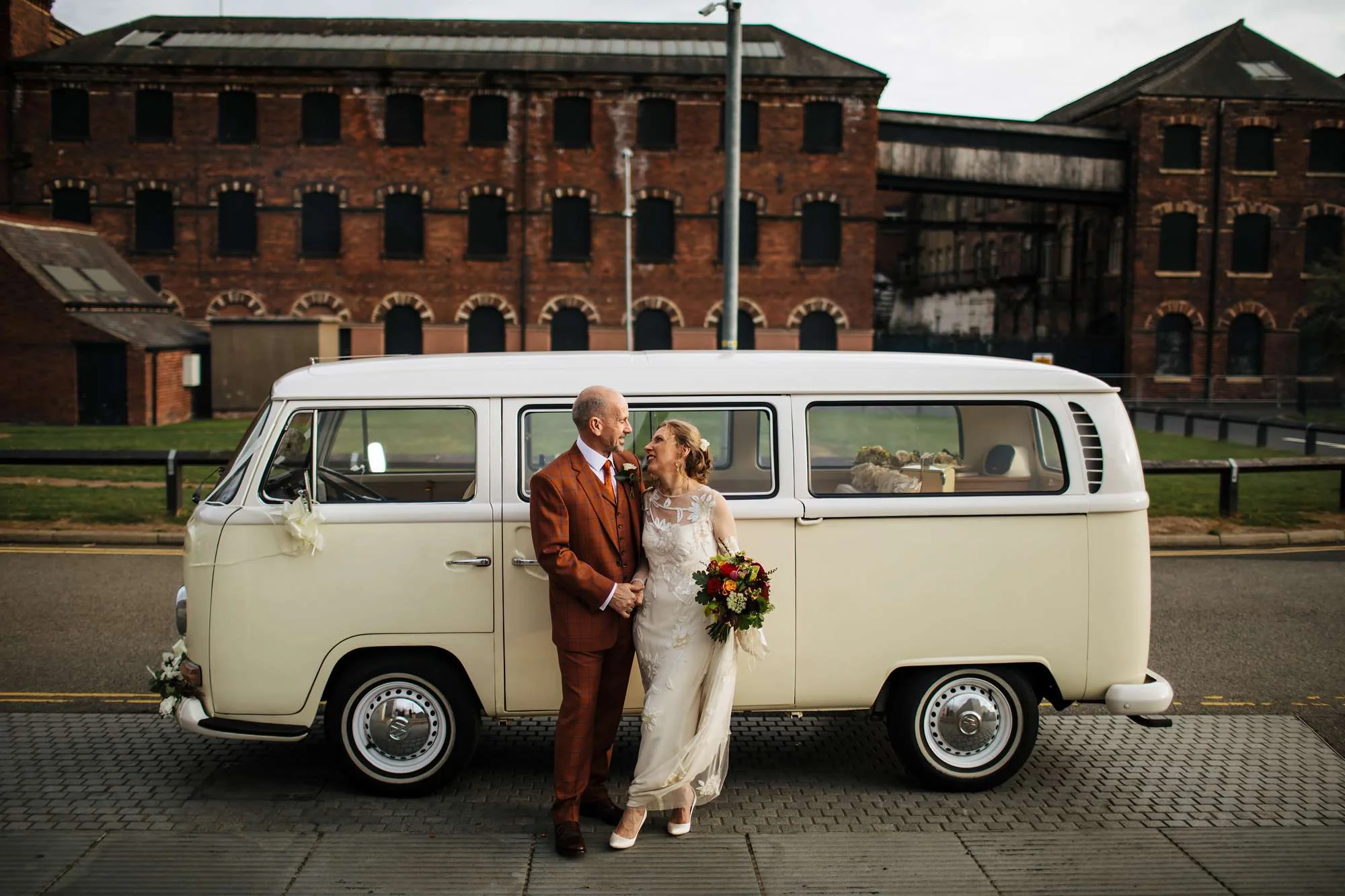 Bride and groom holding hands in front of a VW campervan