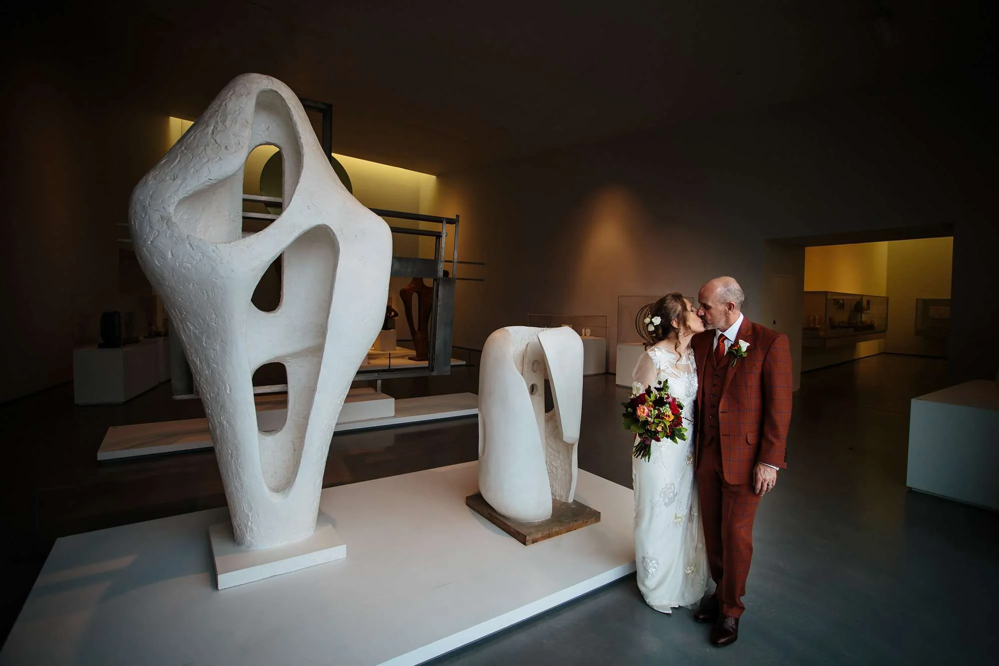 Bride and groom kissing amongst the sculptures at Hepworth Art Gallery