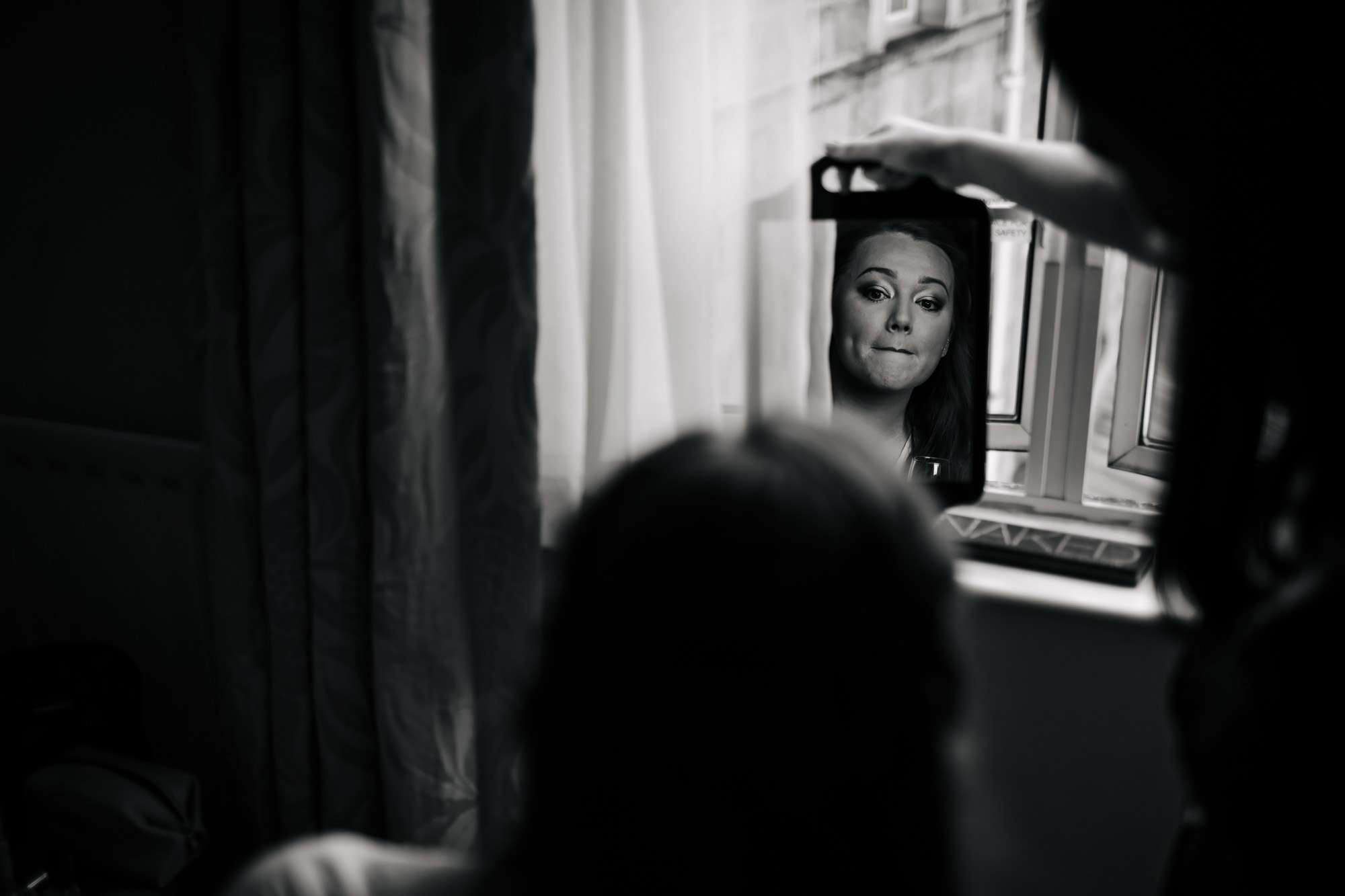 Bride looking in the mirror as her make up is applied