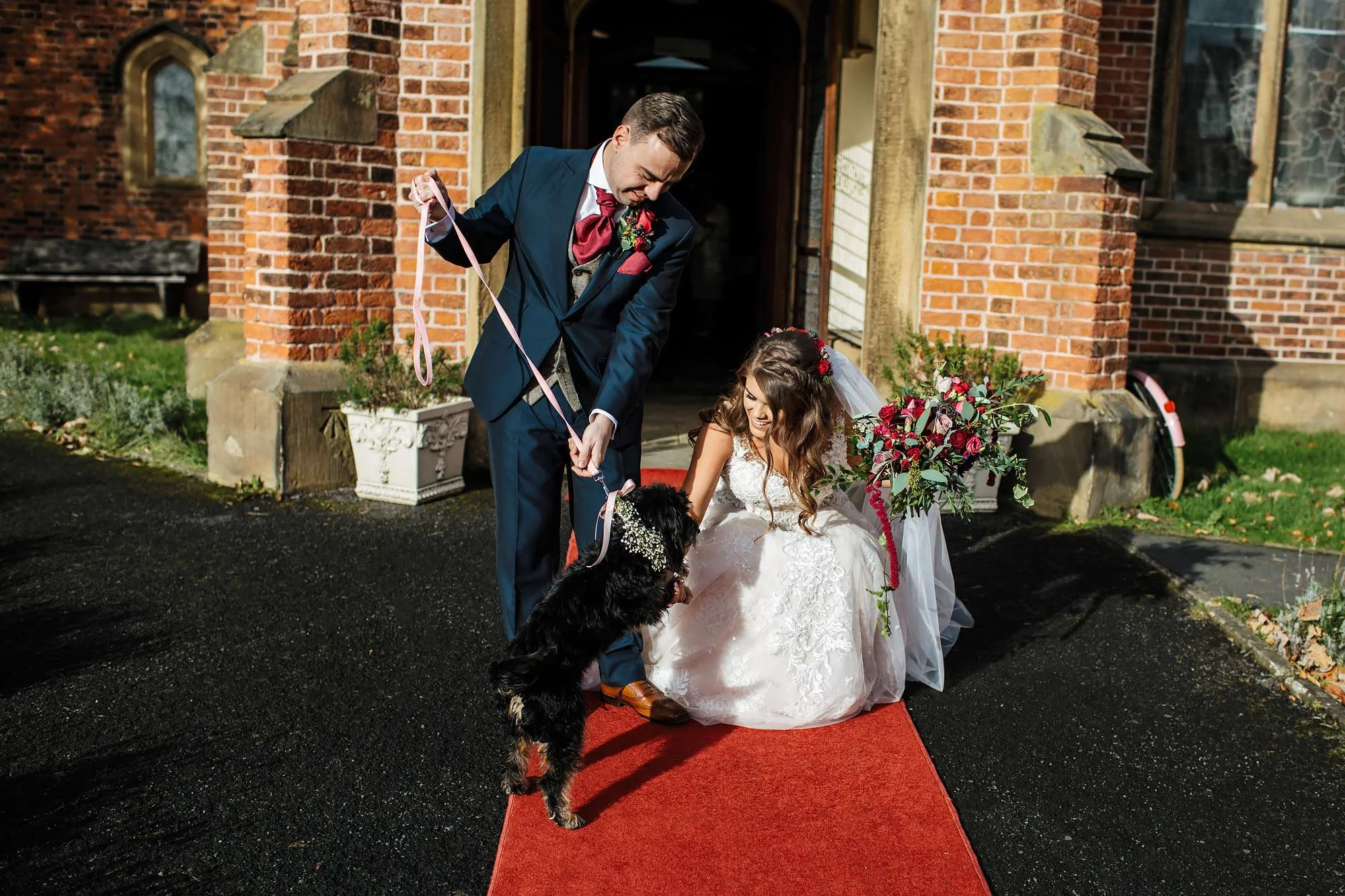 Bride and groom pose with their dog at the wedding