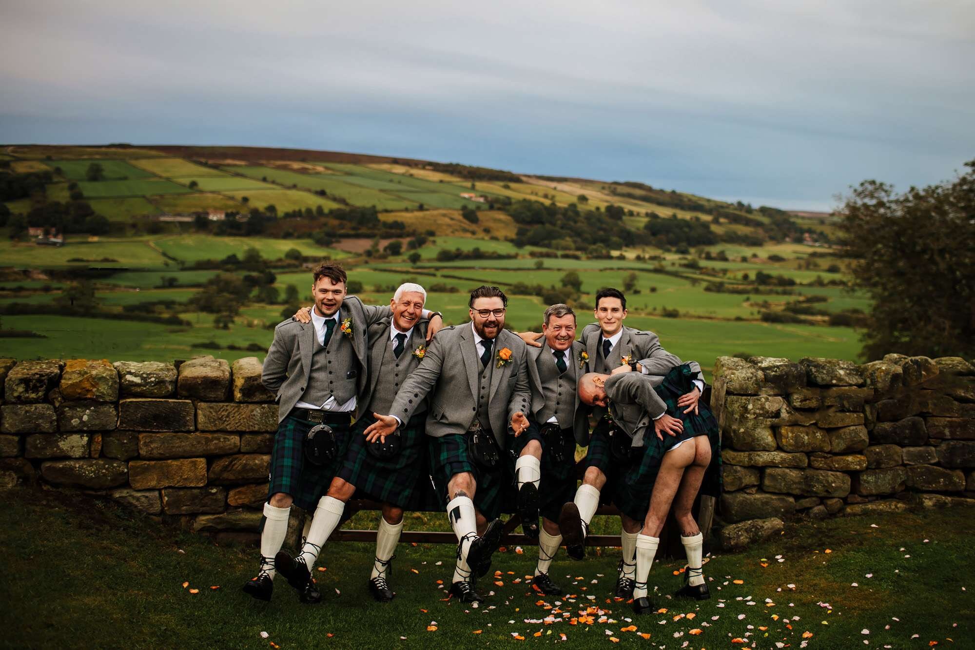 Men in kilts posing as one shows his bum