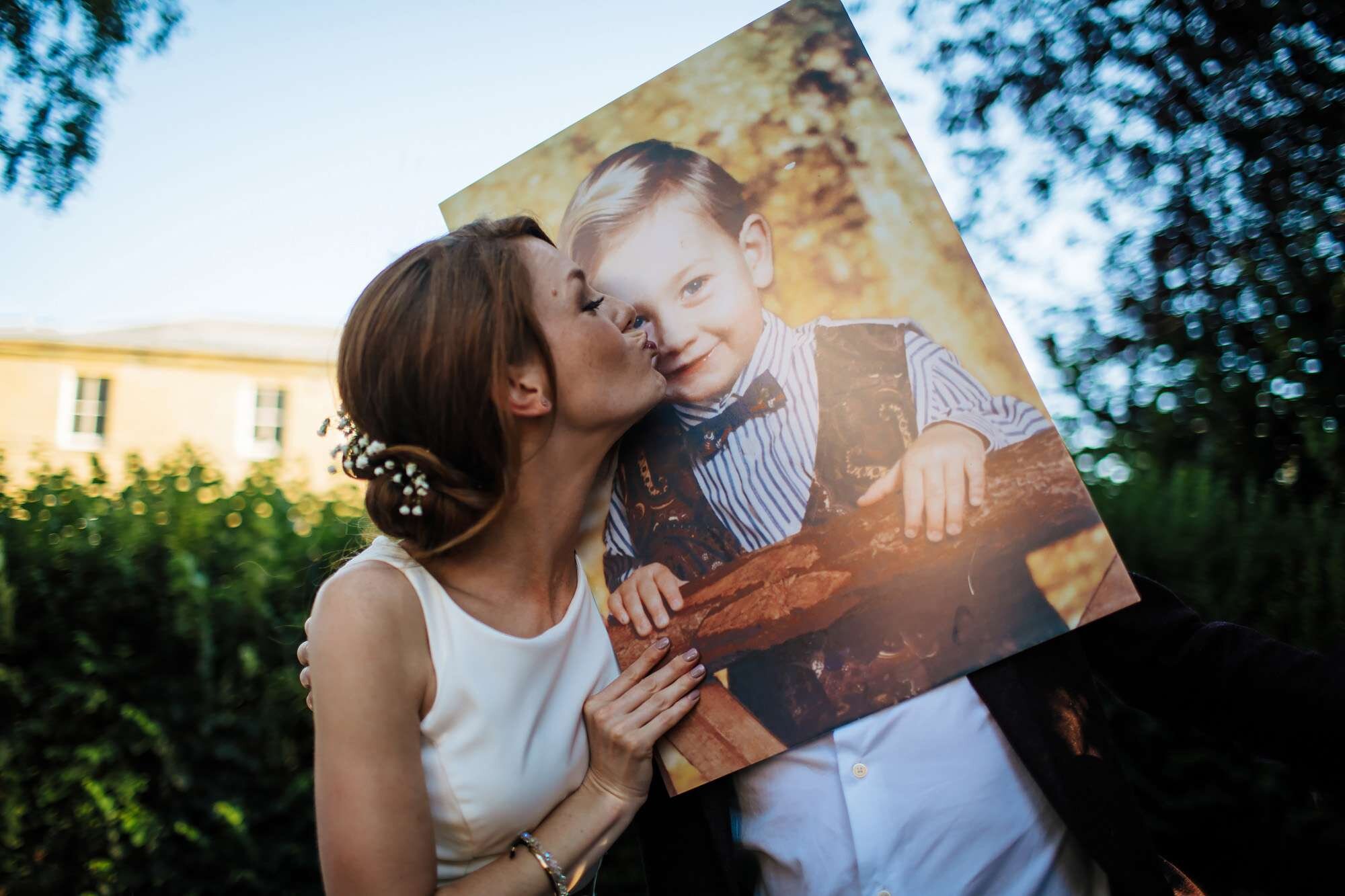 Bride kisses a grooms baby photo at her wedding