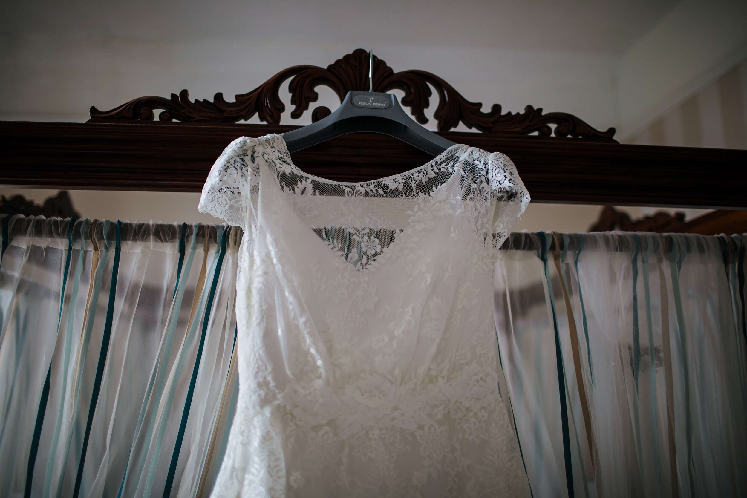 Wedding dress hanging up on a bed