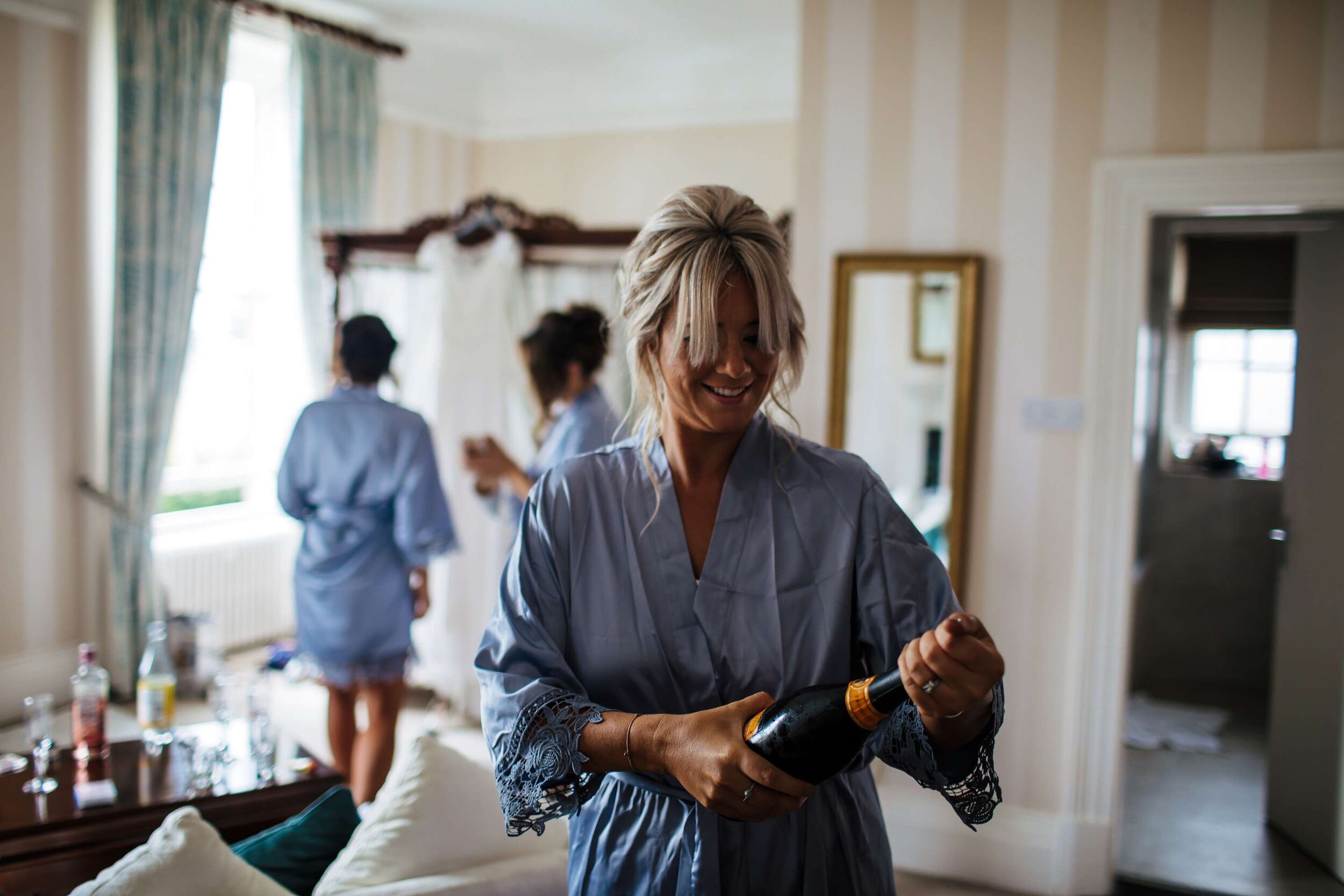 Bridesmaid opening a bottle of champagne on the wedding morning