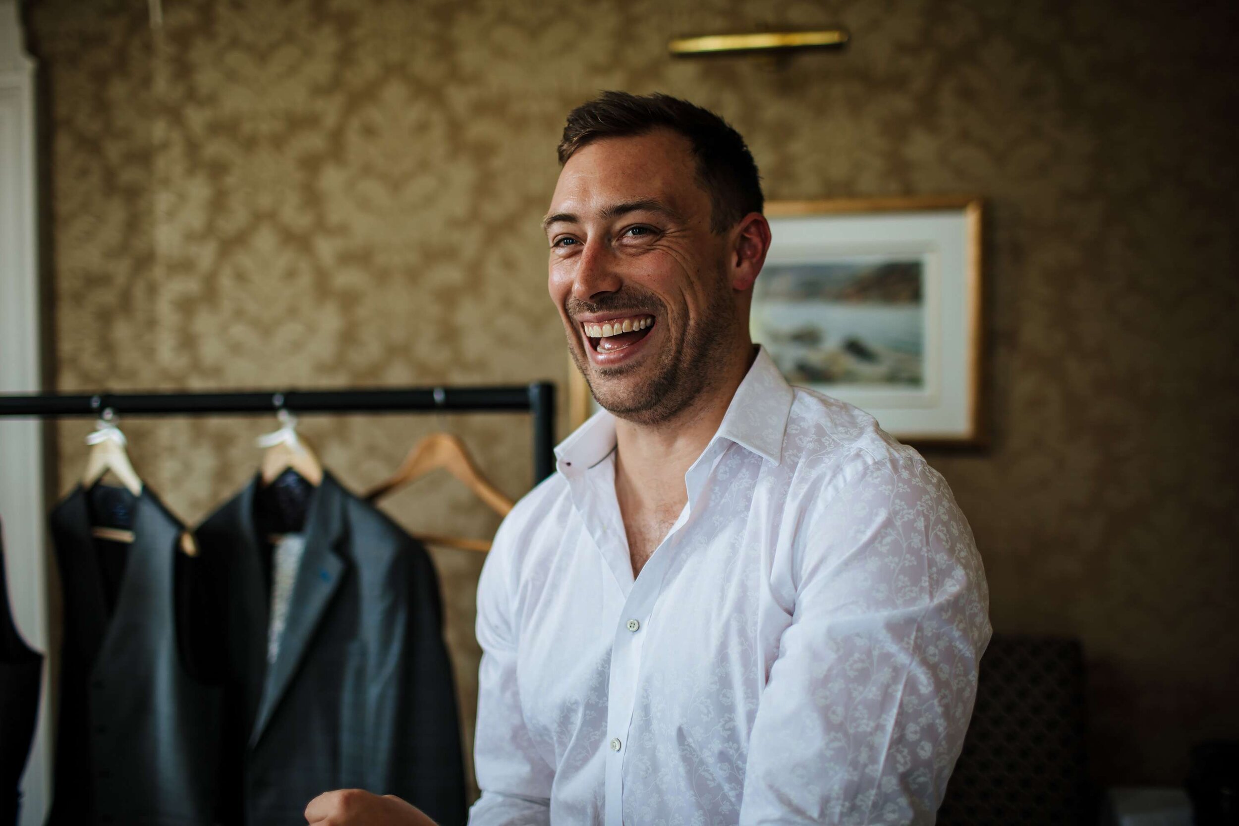 Groom laughing as he gets dressed at Solberge Hall