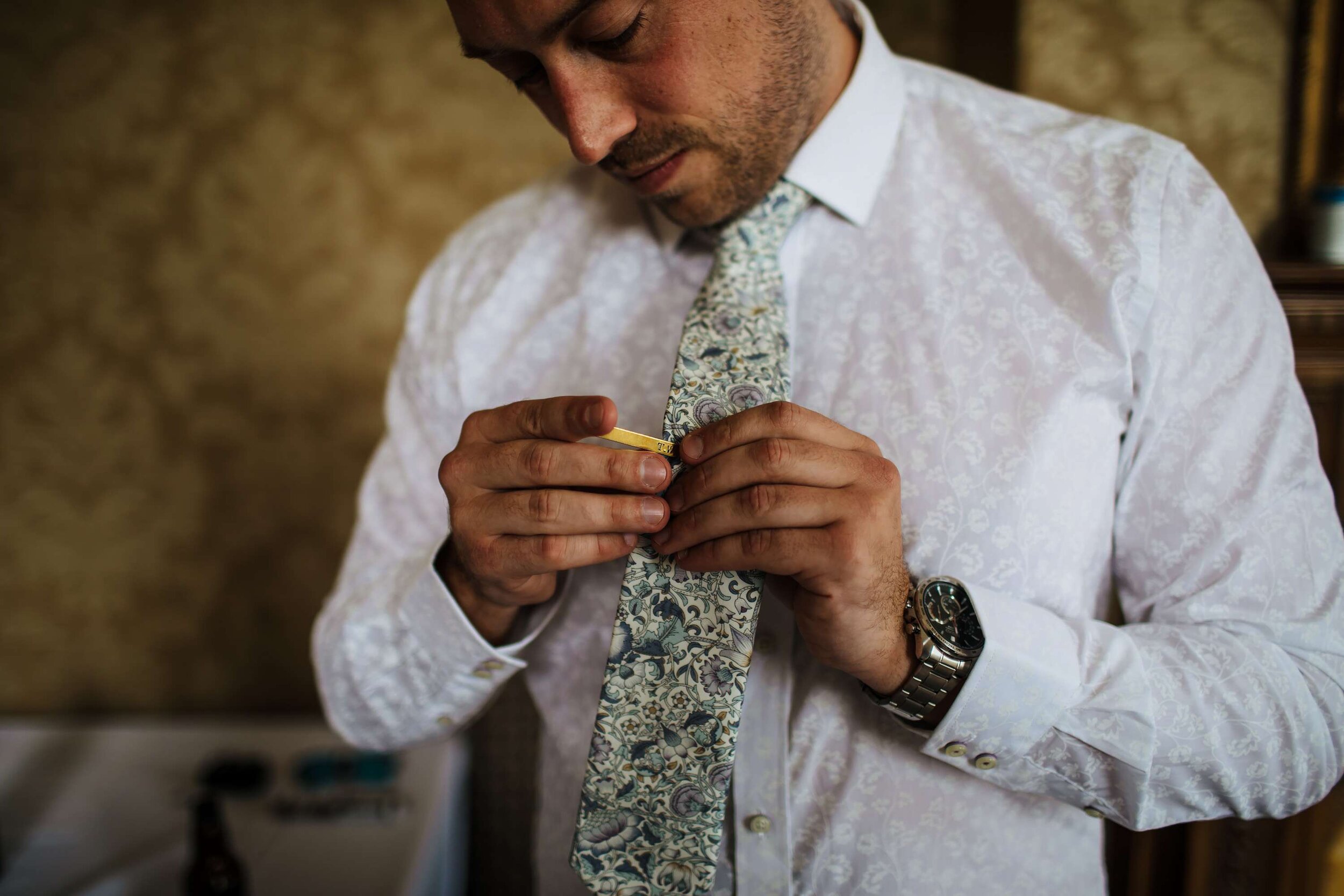 Groom attaching his tie clip at his wedding