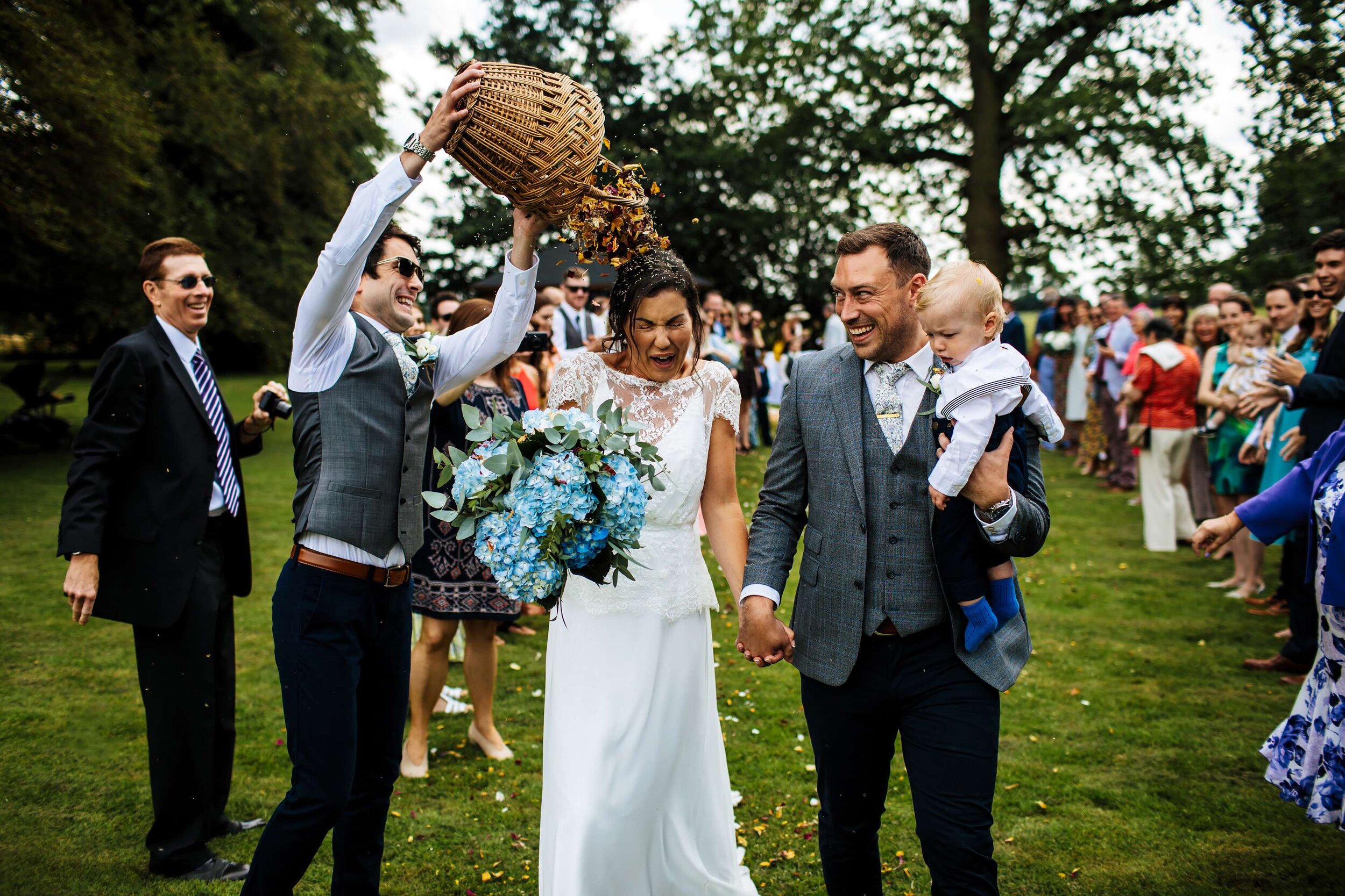 Groomsman throws a full bucket of confetti over the bride