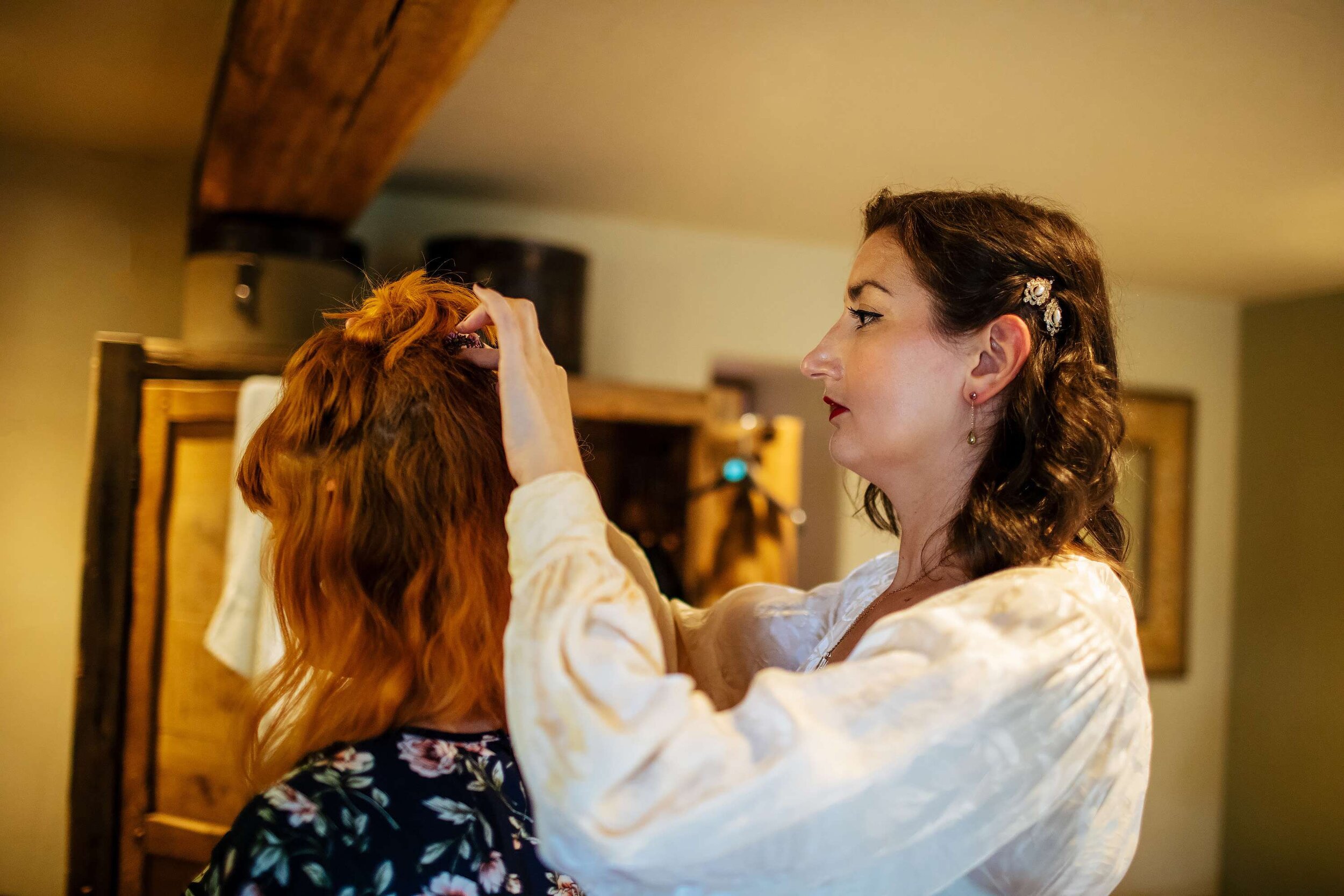 Bride helping her bridesmaid with her hair