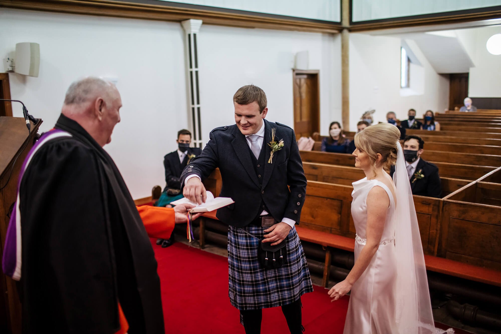 Groom reaches for the wedding ring during the ceremony