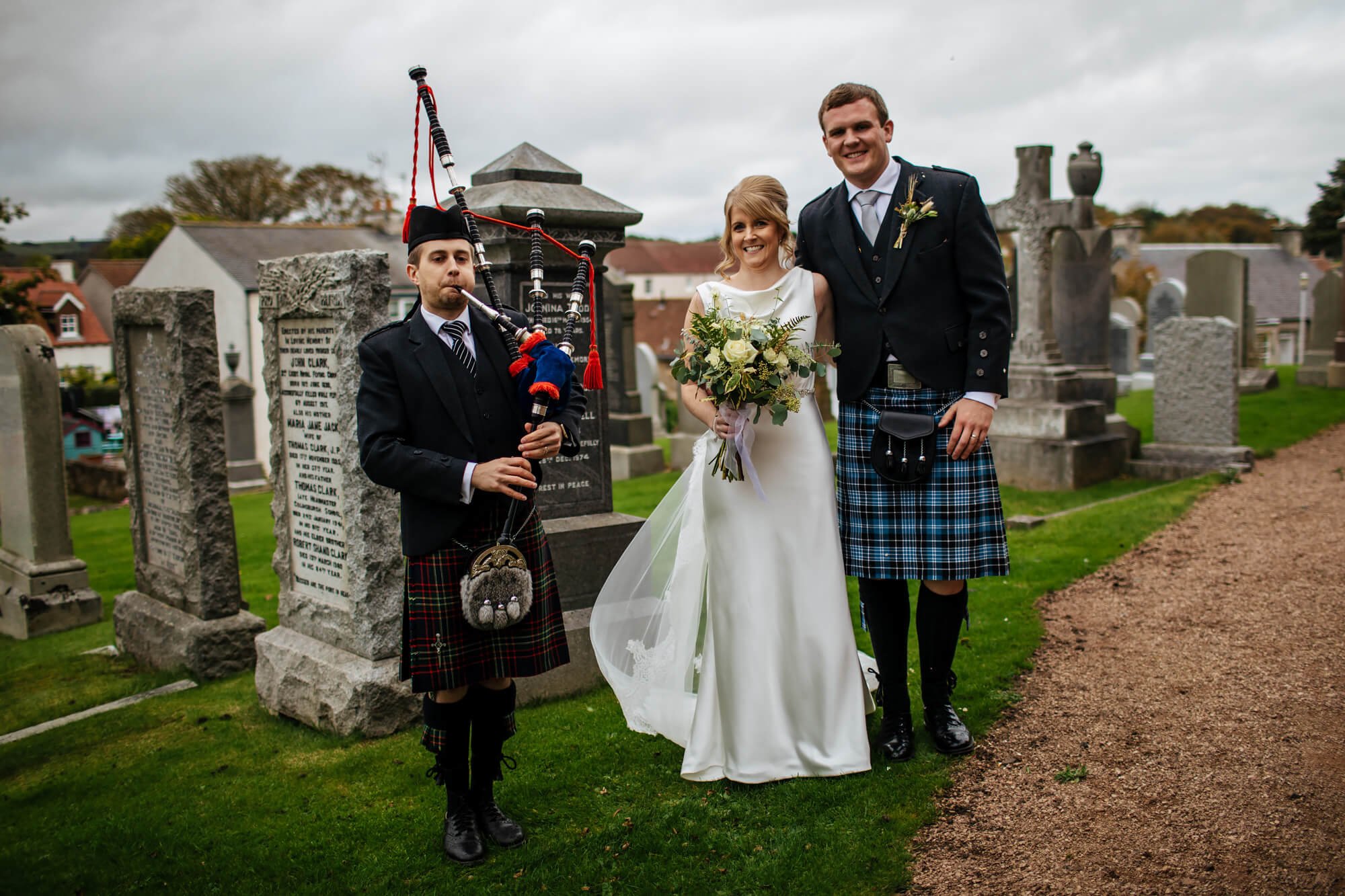 Bride, groom and piper at a Scottish farm wedding