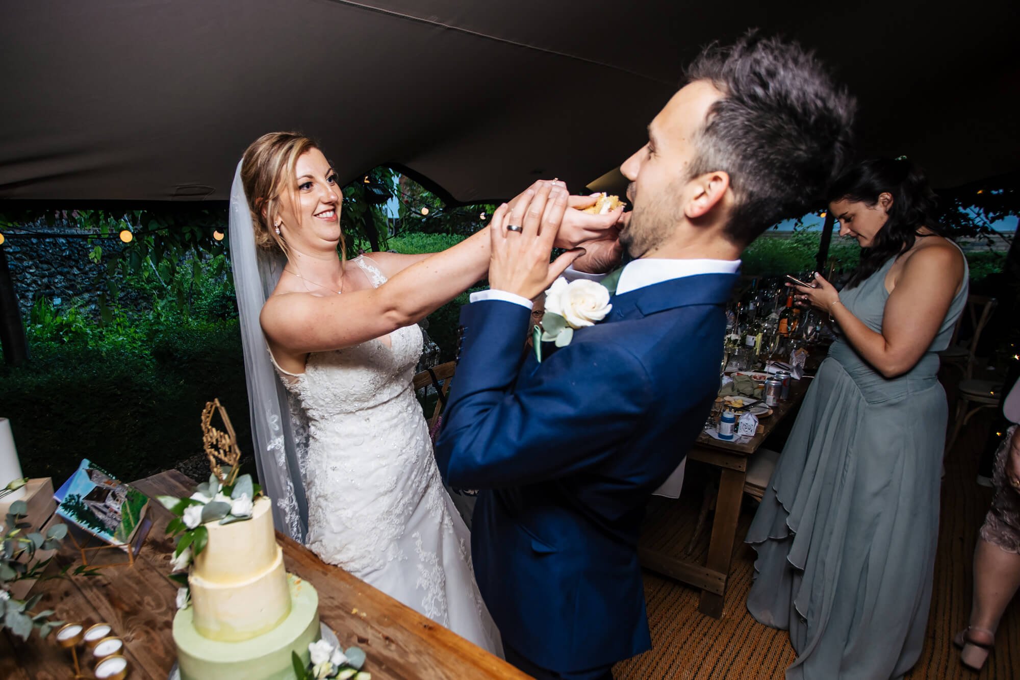 Bride stuffing the cake into the groom's mouth at a wedding