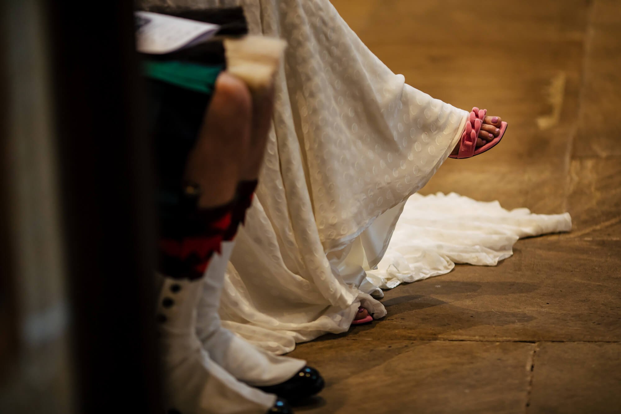 Bride's shoes poking out form under her wedding dress