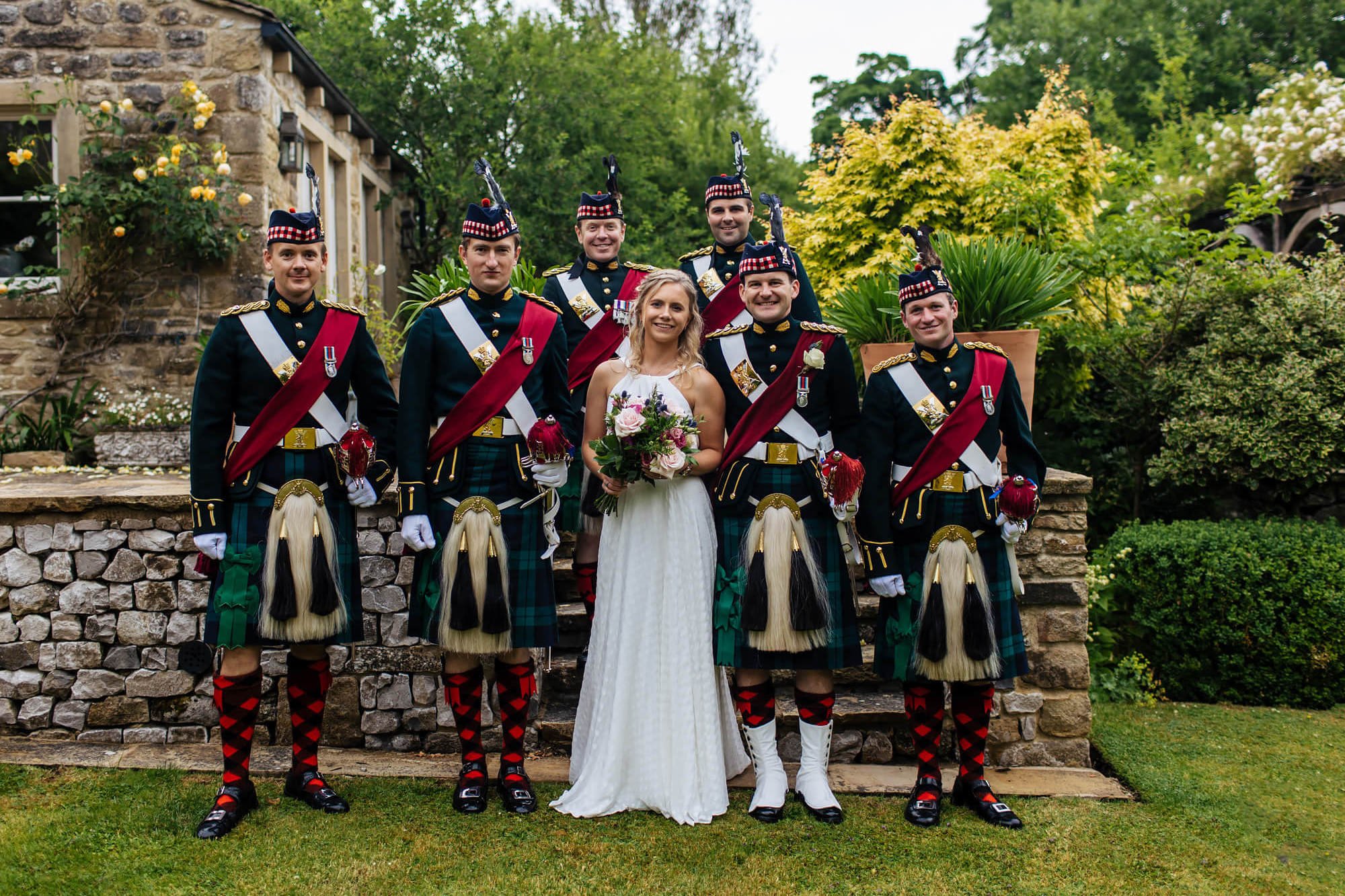 Bride and groom posing with the groomsmen in military kilts