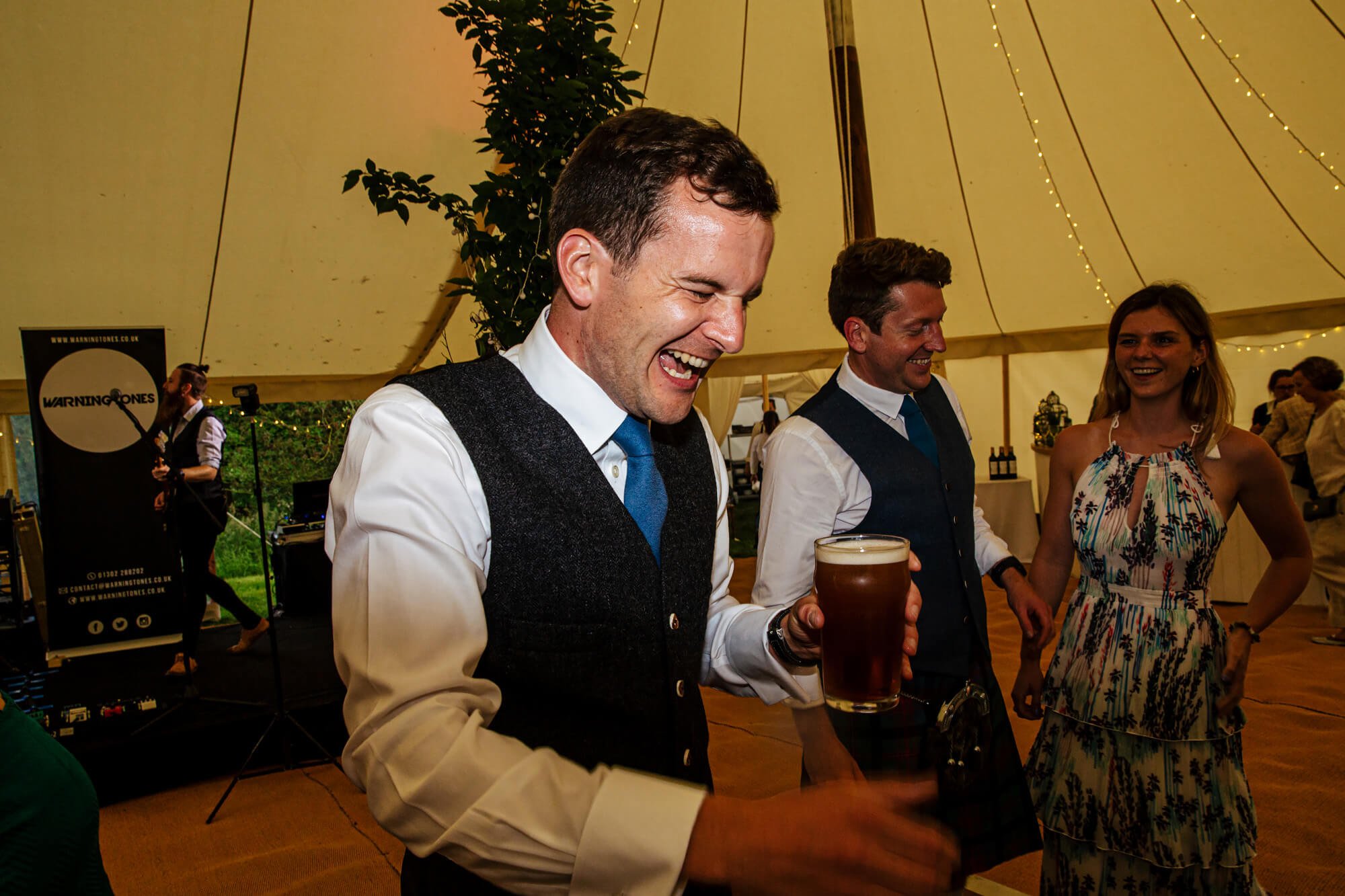 Groom laughing with friends at his wedding