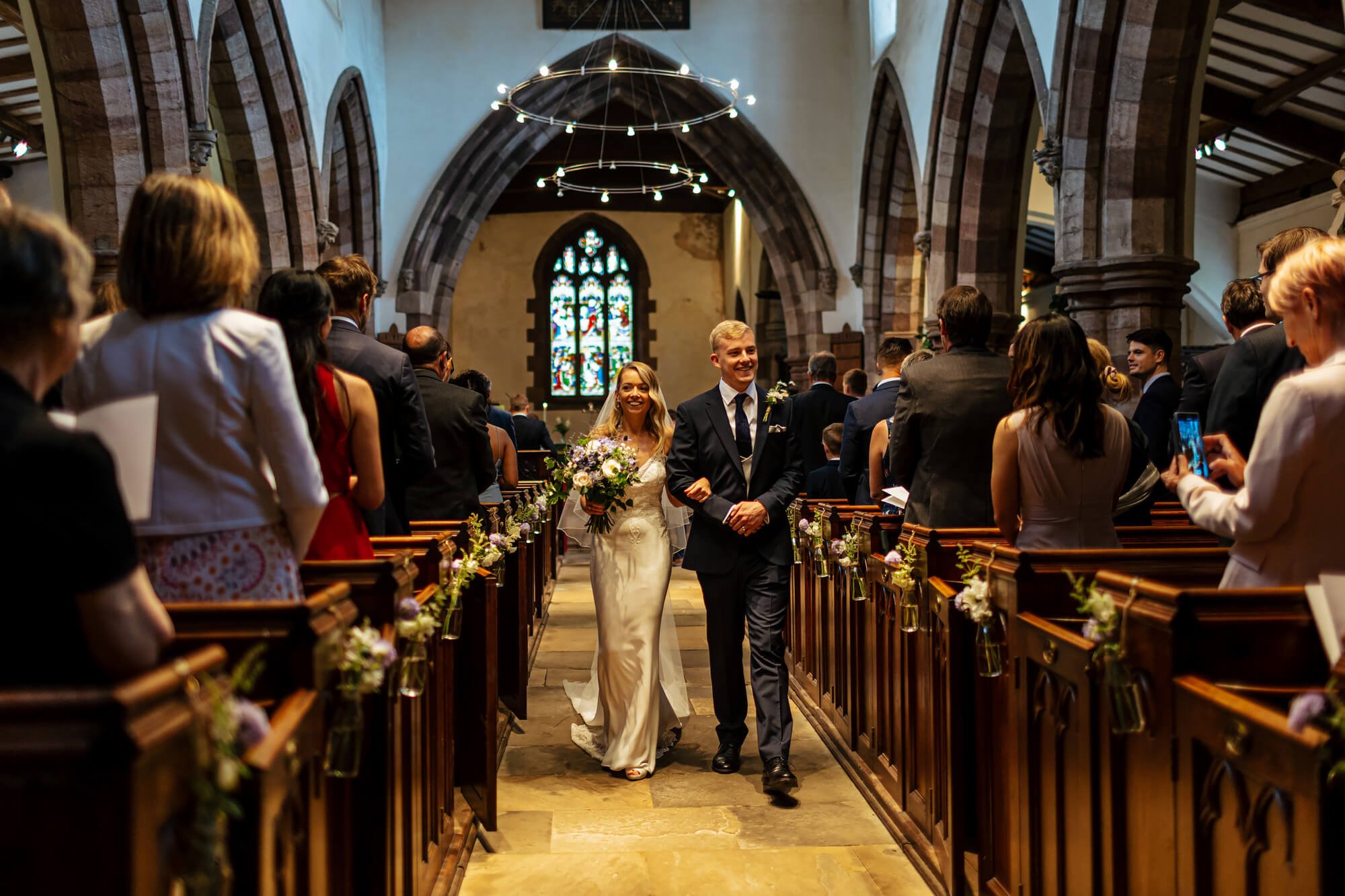 Bride and groom walking down the church aisle in Cumbria