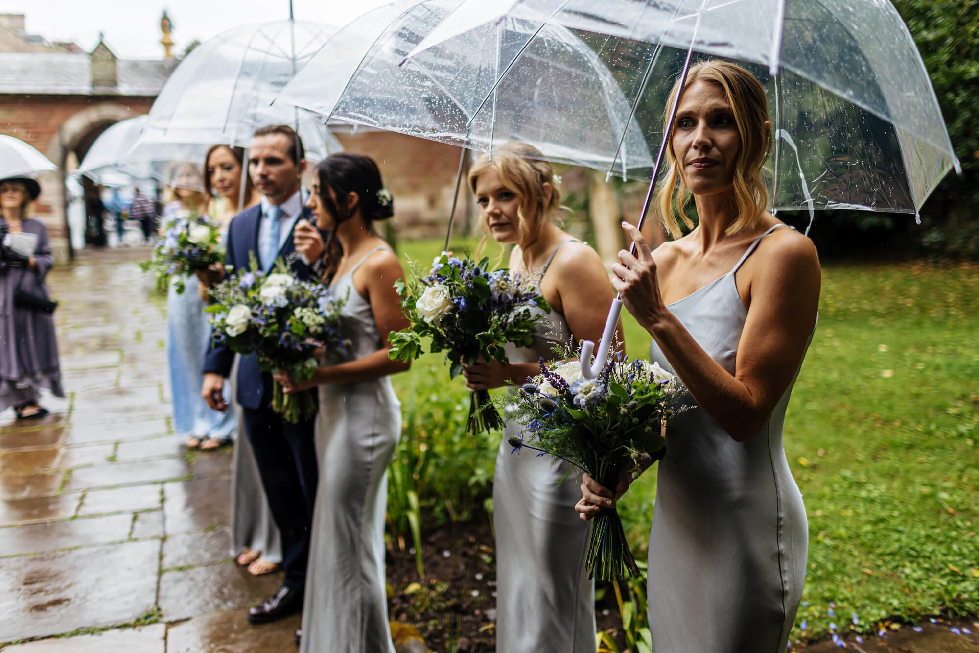 Bridesmaids waiting in the rain at the church yard