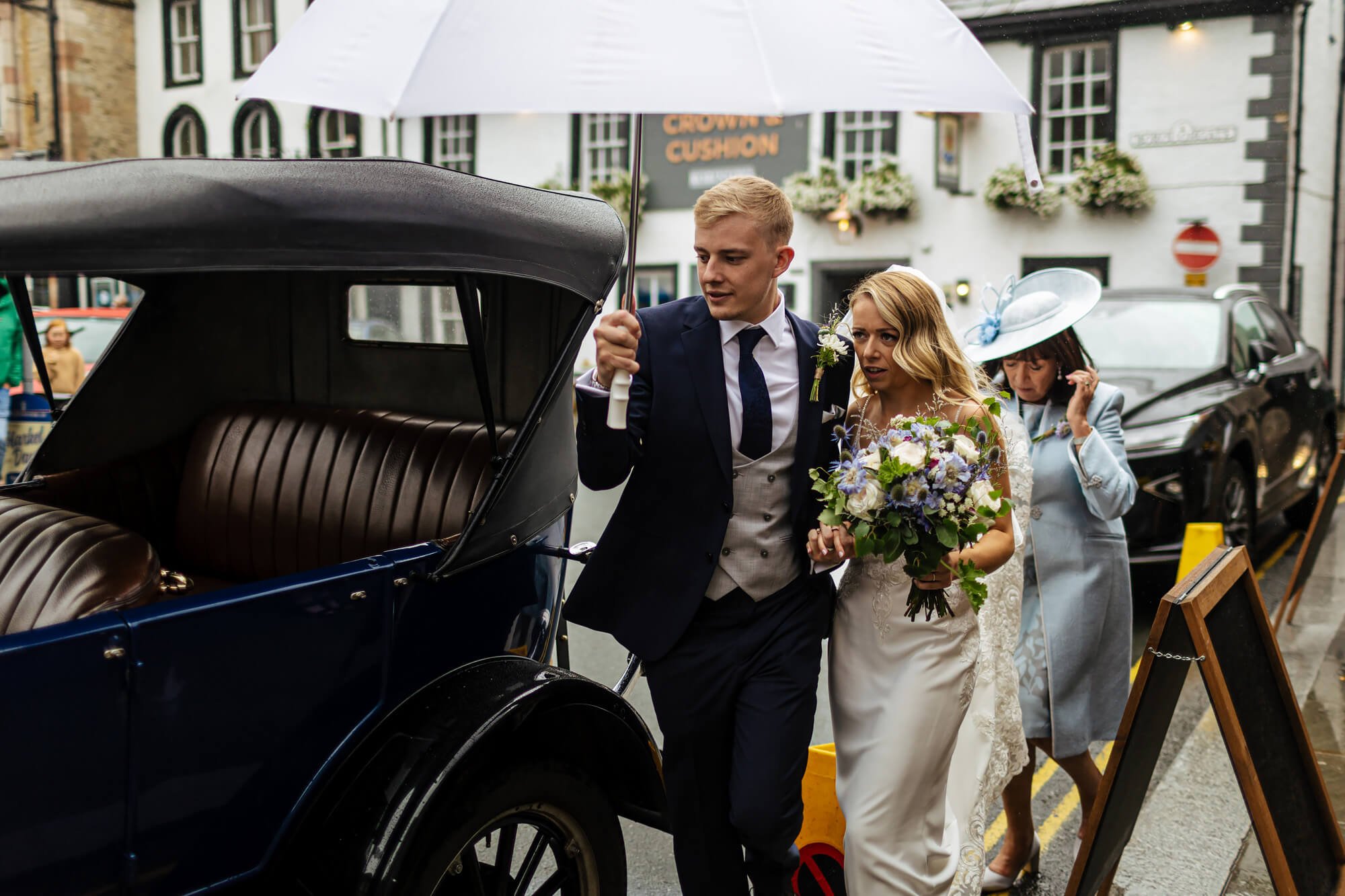 Bride and groom getting into a vintage car after their wedding