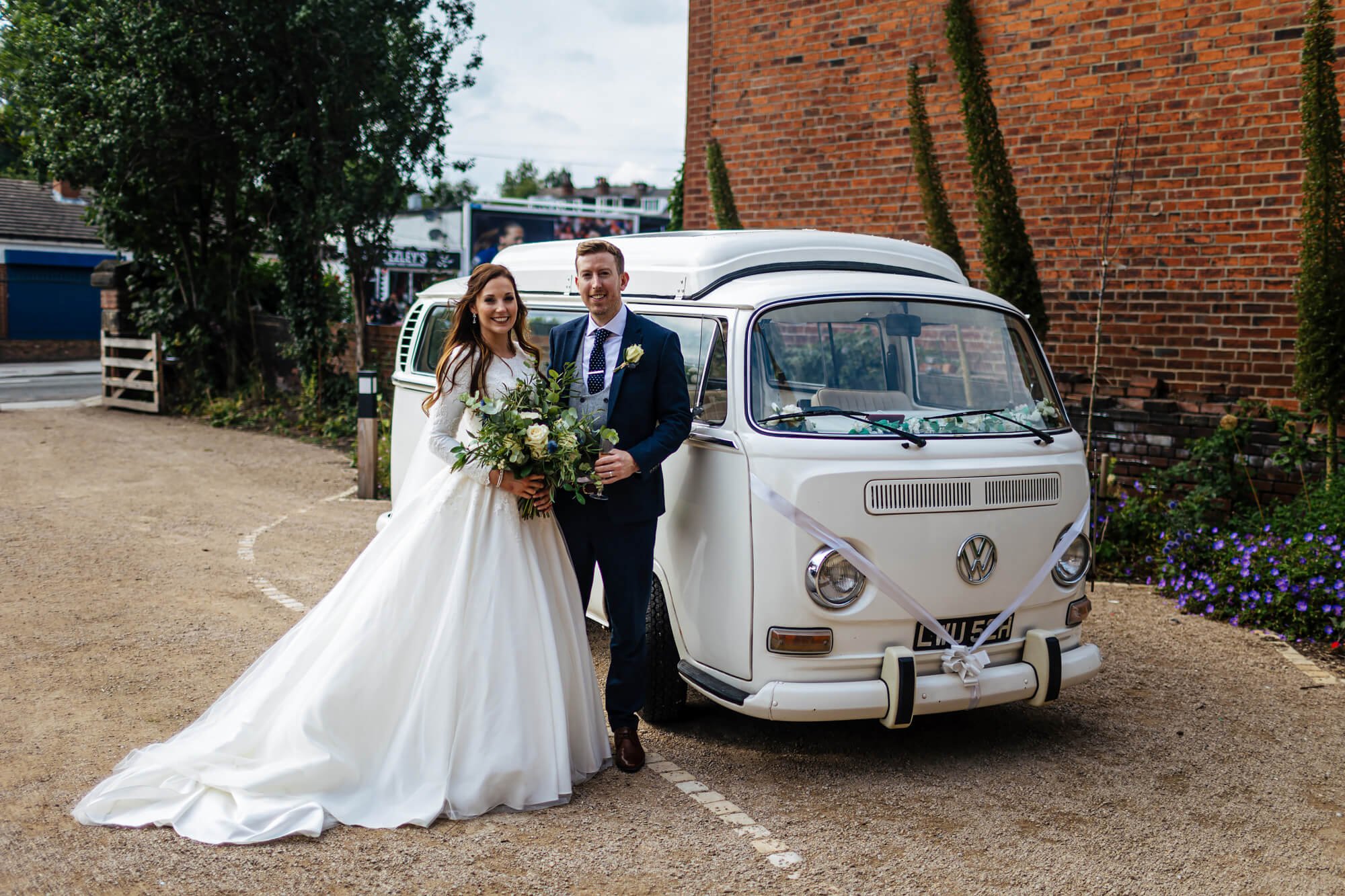 Bride and groom with their VW campervan at their wedding