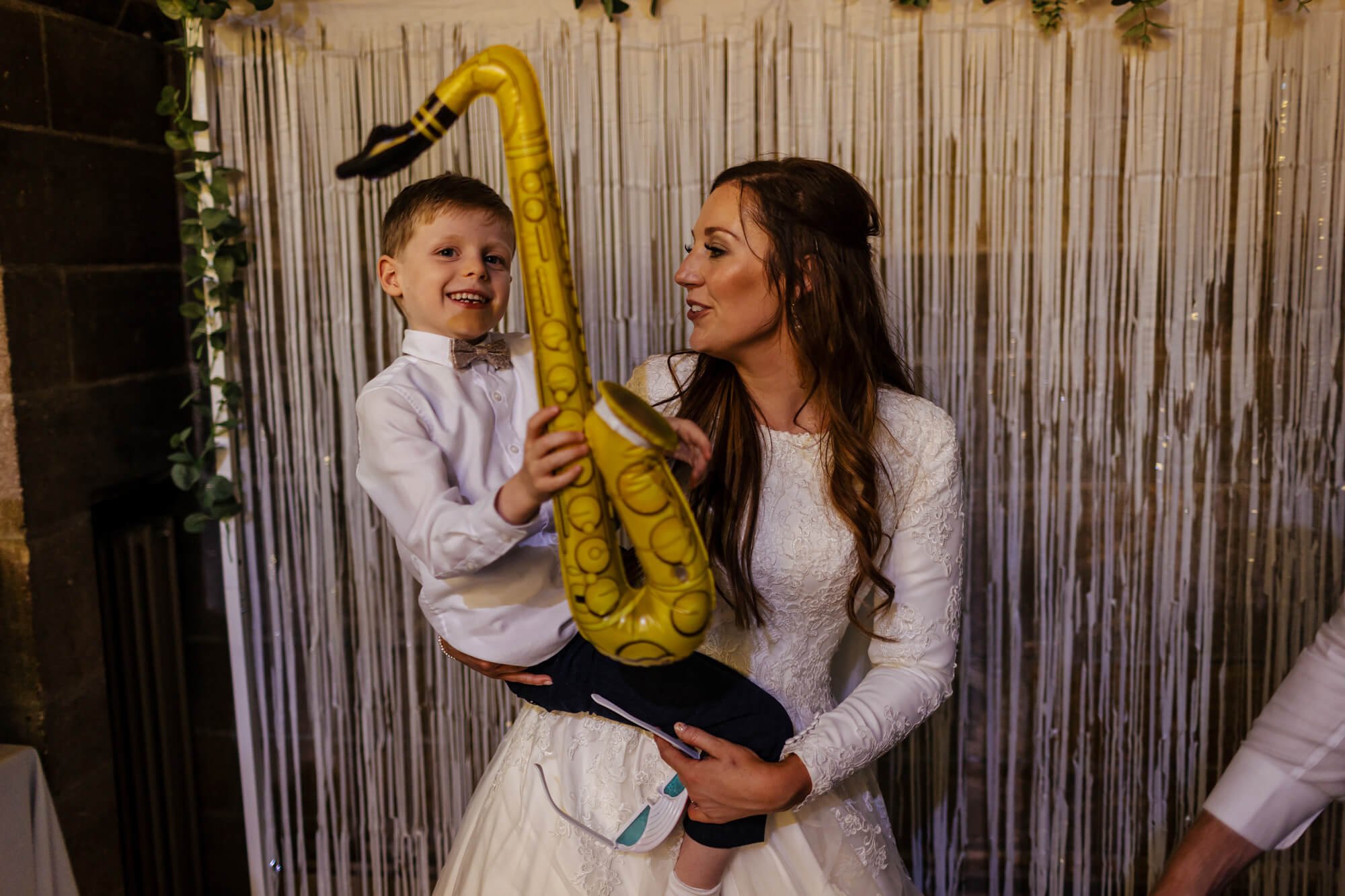 Bride and young boy pose with a blow up saxophone