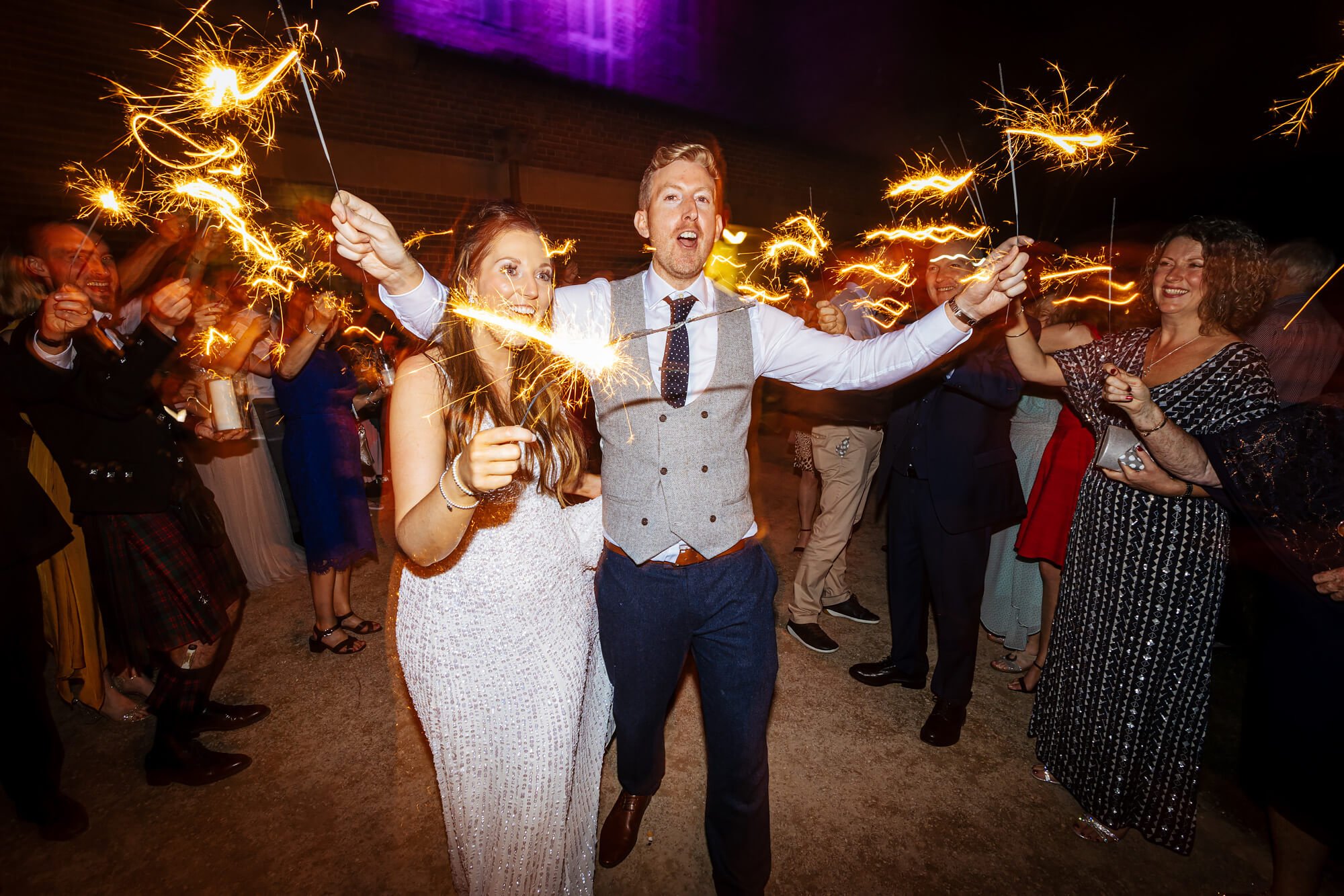 Bride and groom walk though a line of sparklers