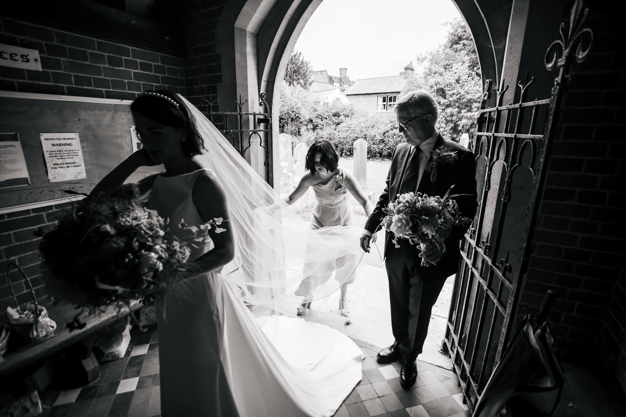 Bridesmaid helps the bride with her veil at the church