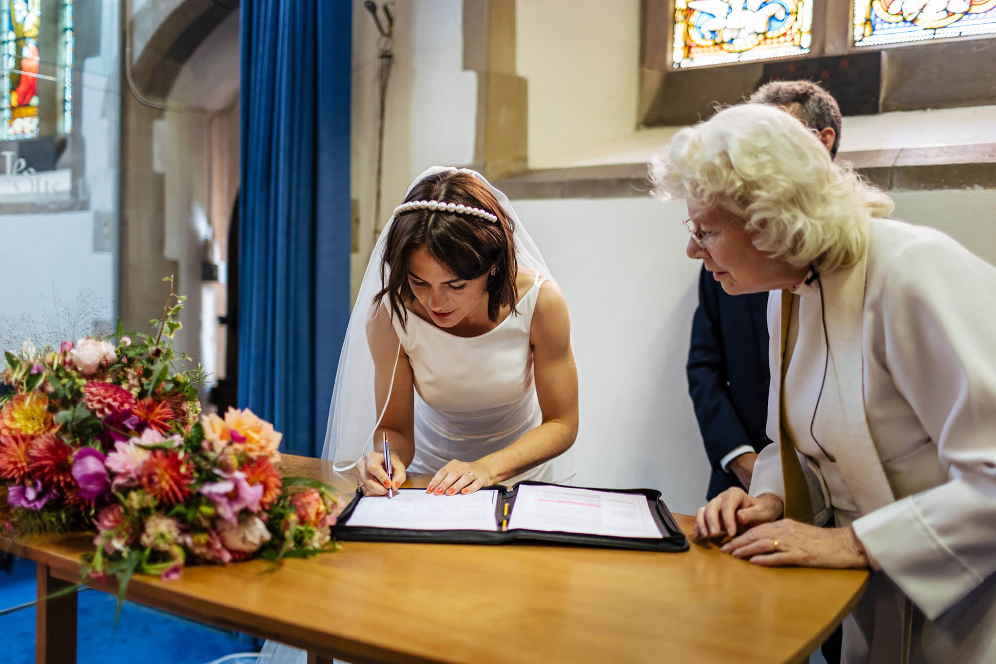 Bride signing the register at her wedding