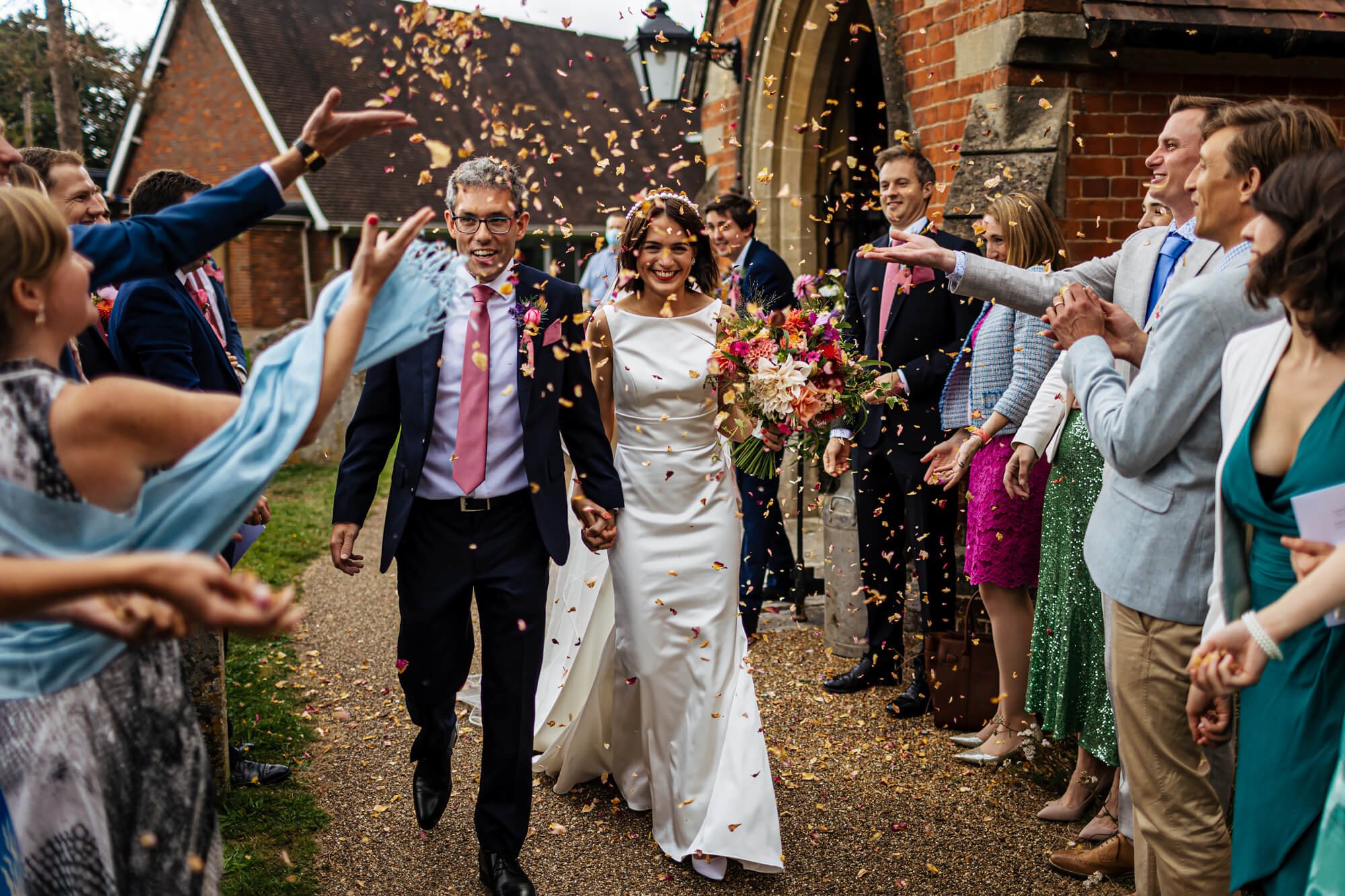 Wedding guests throw confetti over the bride and groom