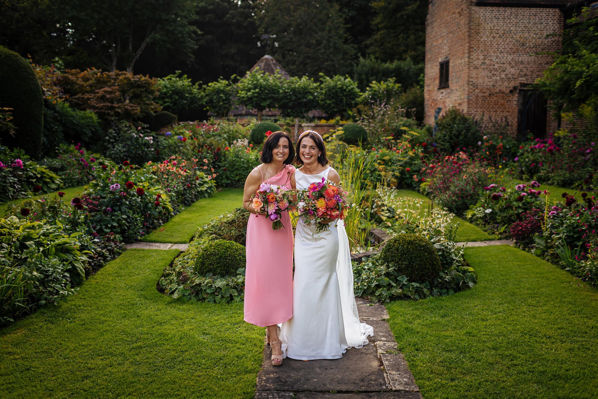 Bride and her bridesmaid pose in the garden