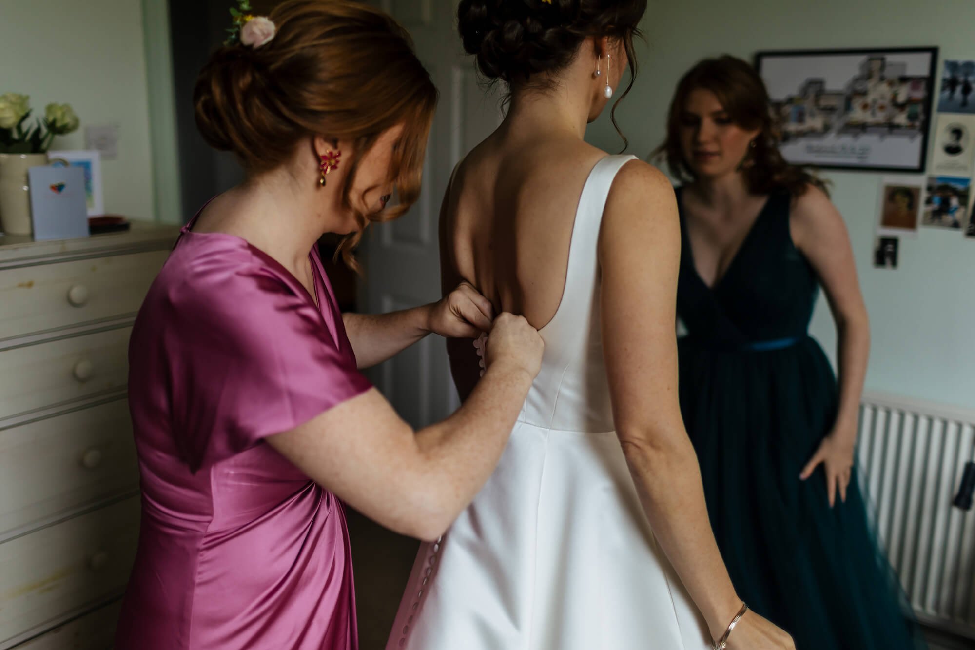 Bridesmaid helping the bride into her wedding dress