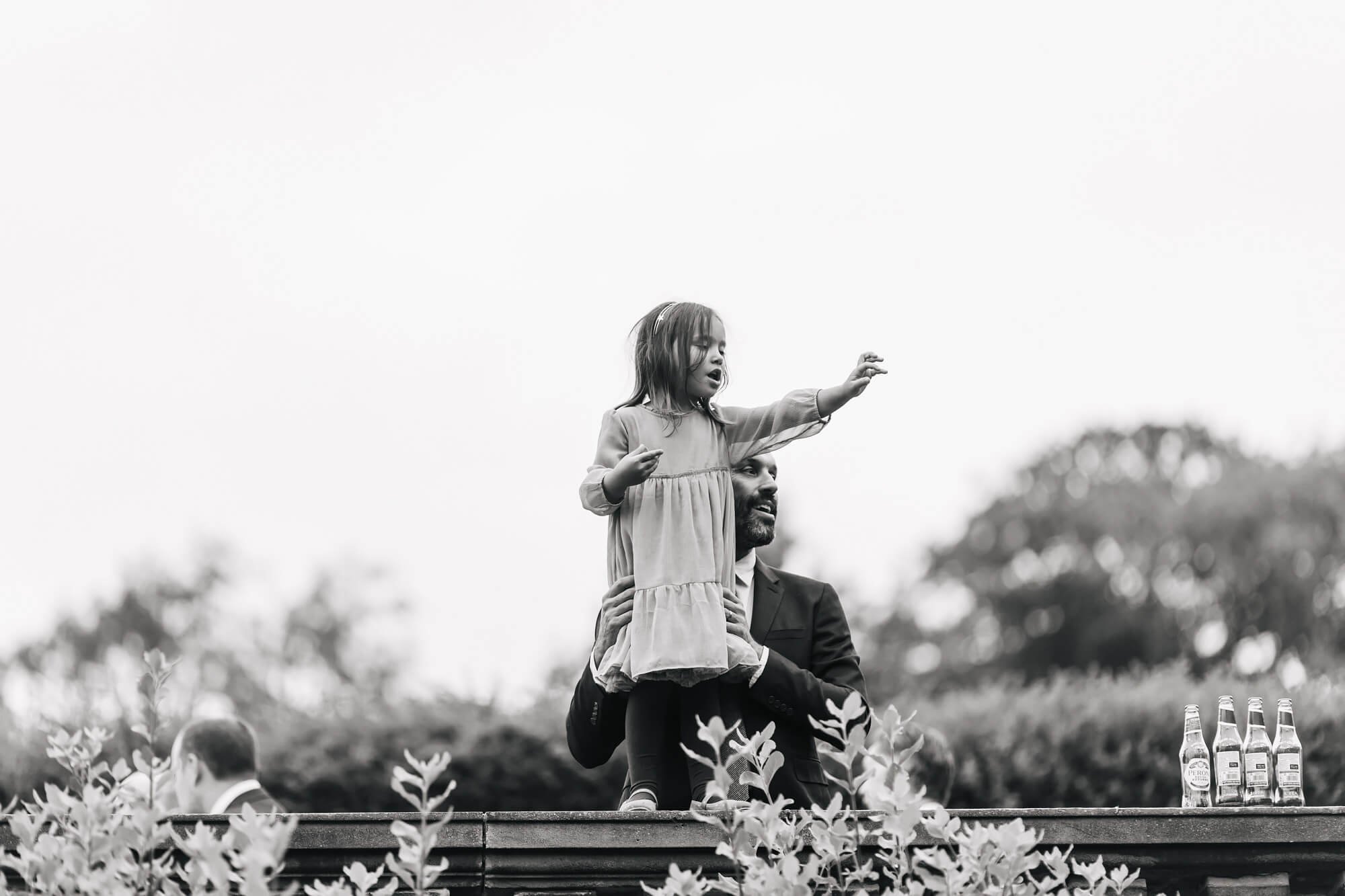 Little girl standing on a wall during the wedding reception