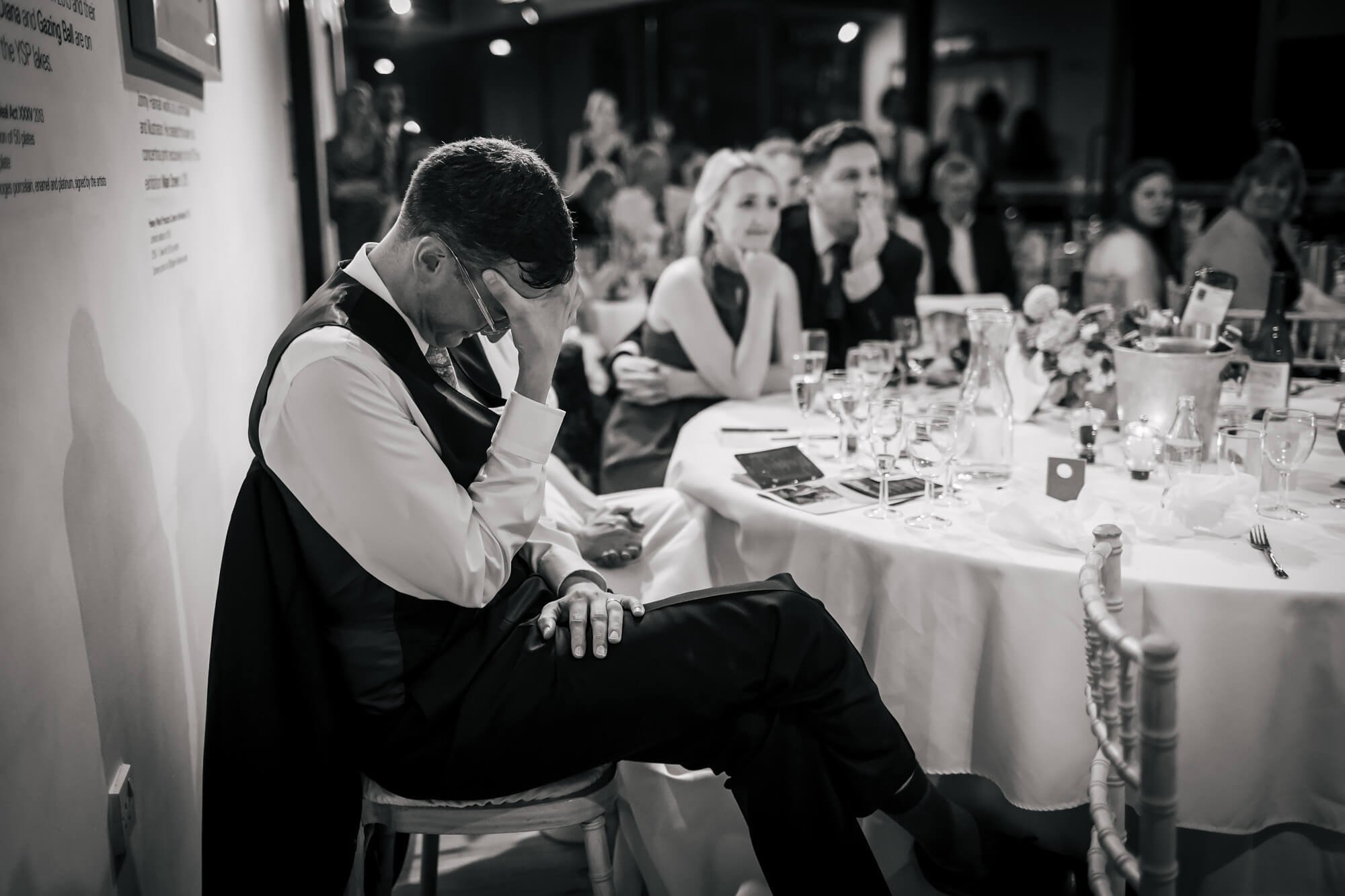 Groom with his head in his hands during the best man's speech