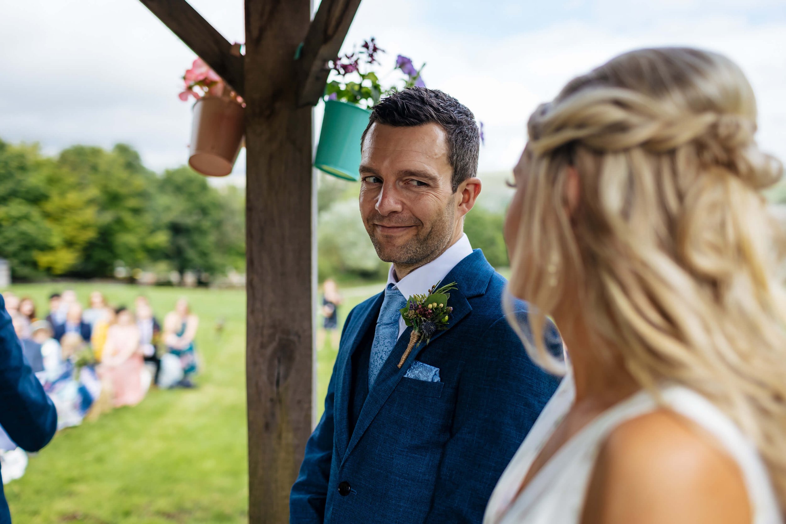 Groom smiling at his bride during the wedding at Kilnsey Park